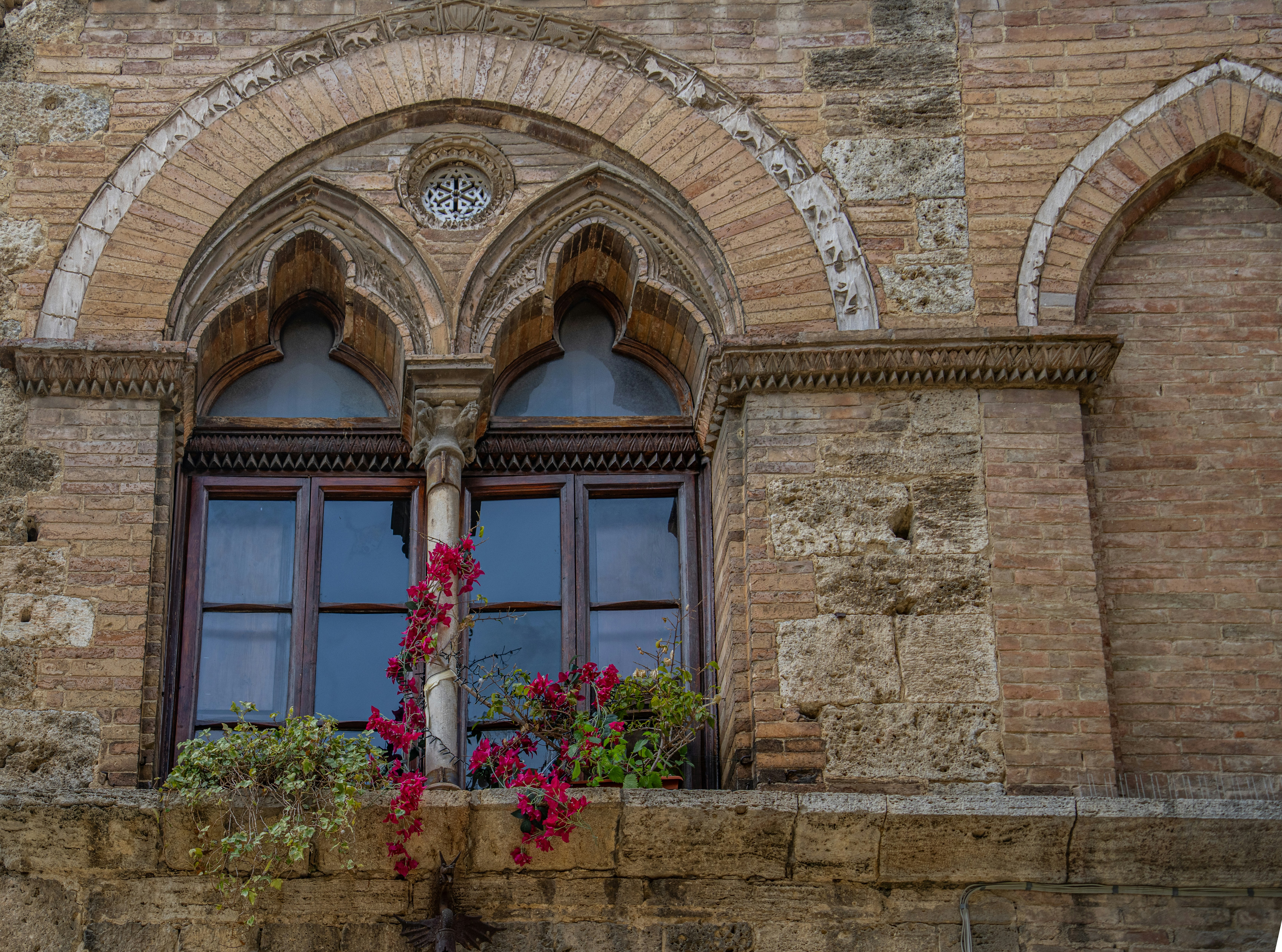 Ornate gothic window with flowering vines on stone building