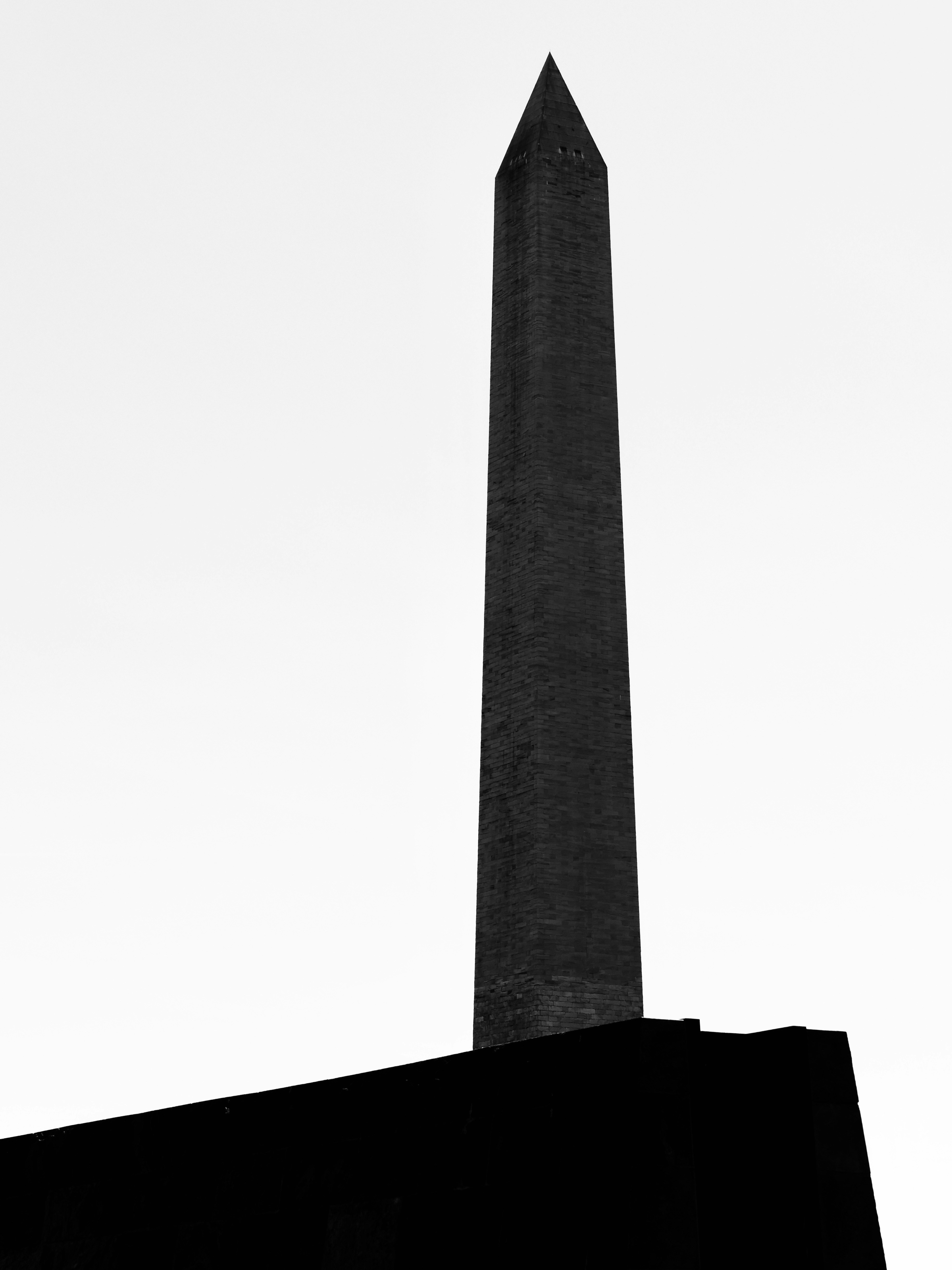 明るい空を背景に背の高い暗いオベリスク。