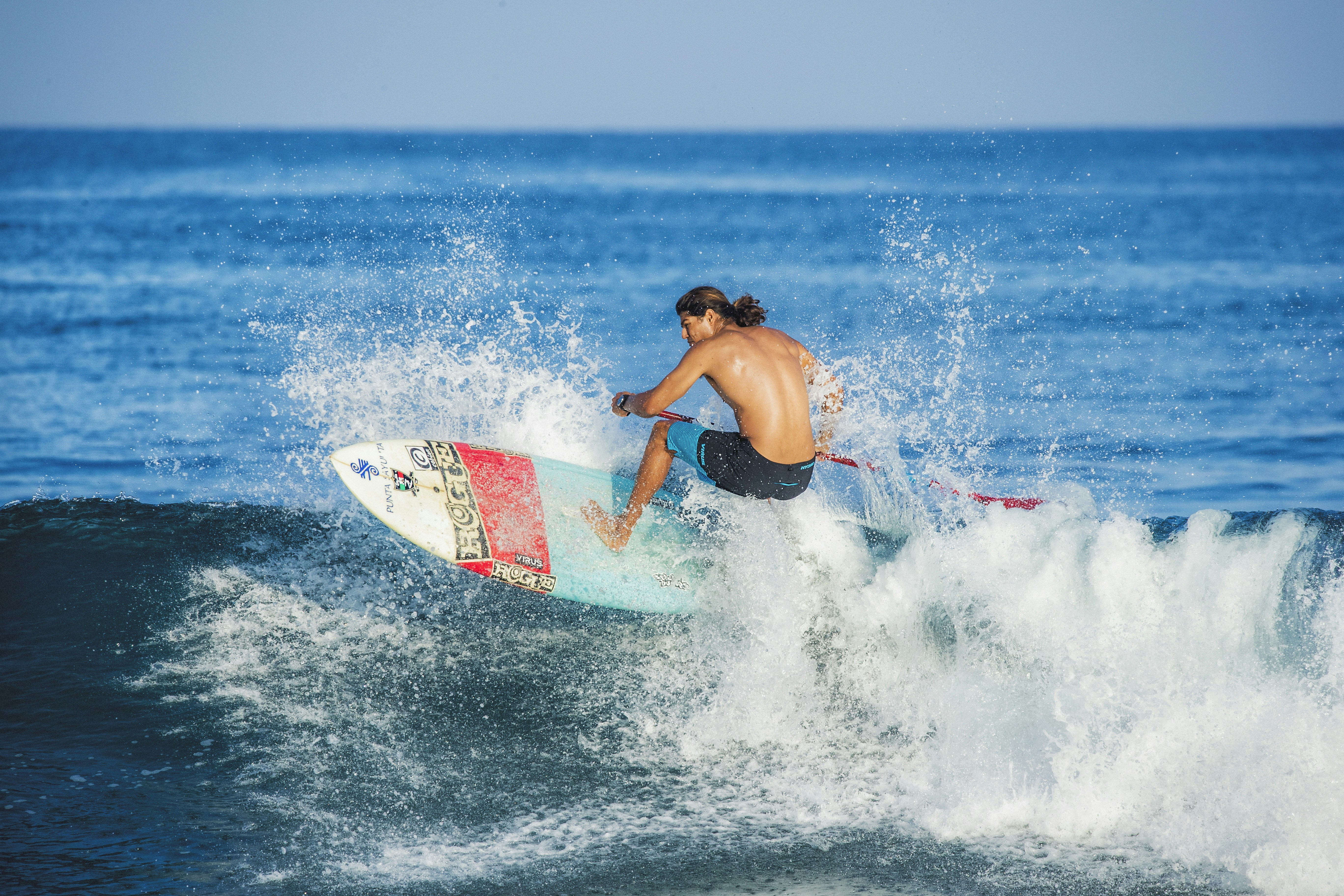 surfer riding a wave, kicking up water