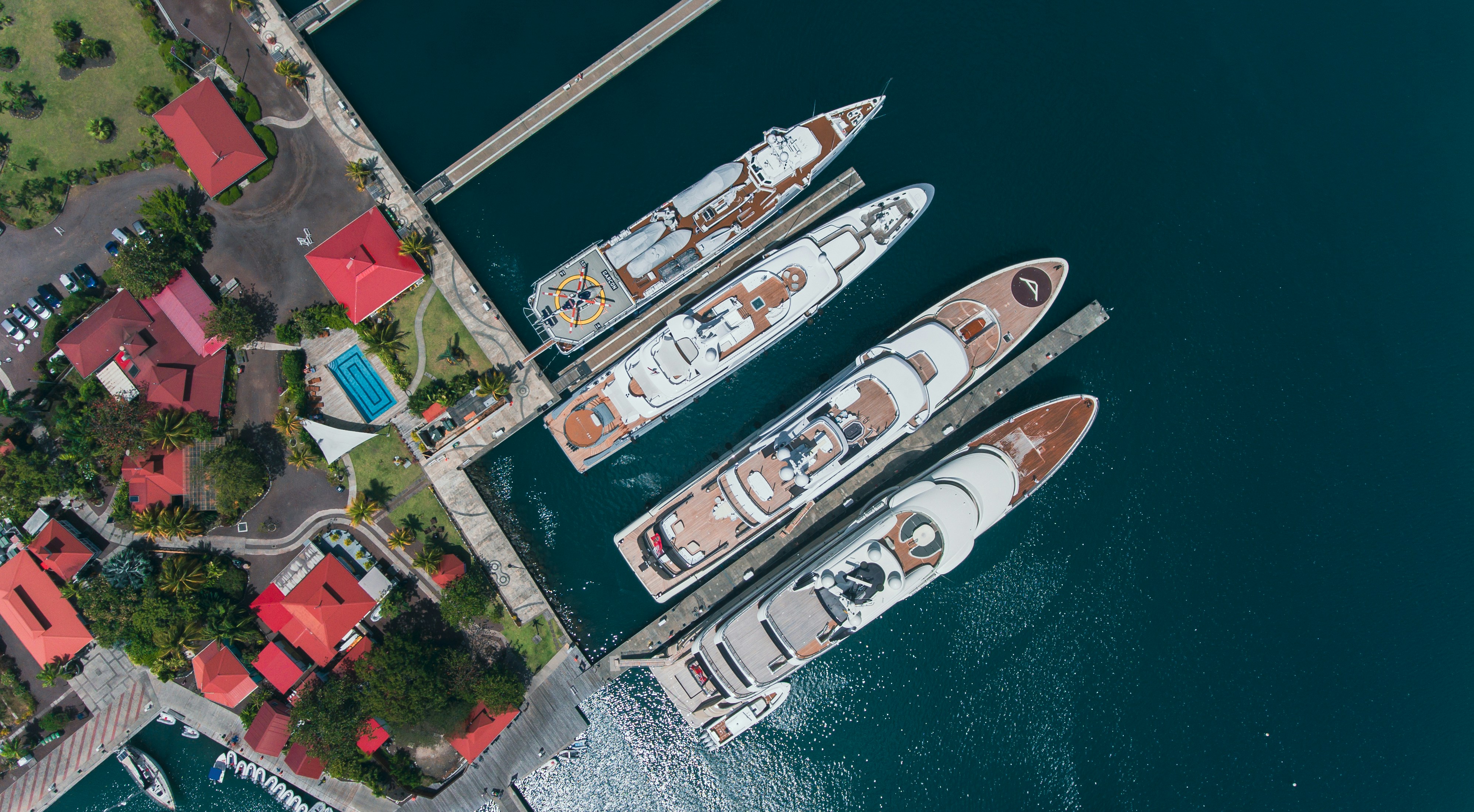 Quatre yachts de luxe accostés dans une marina avec des bâtiments.