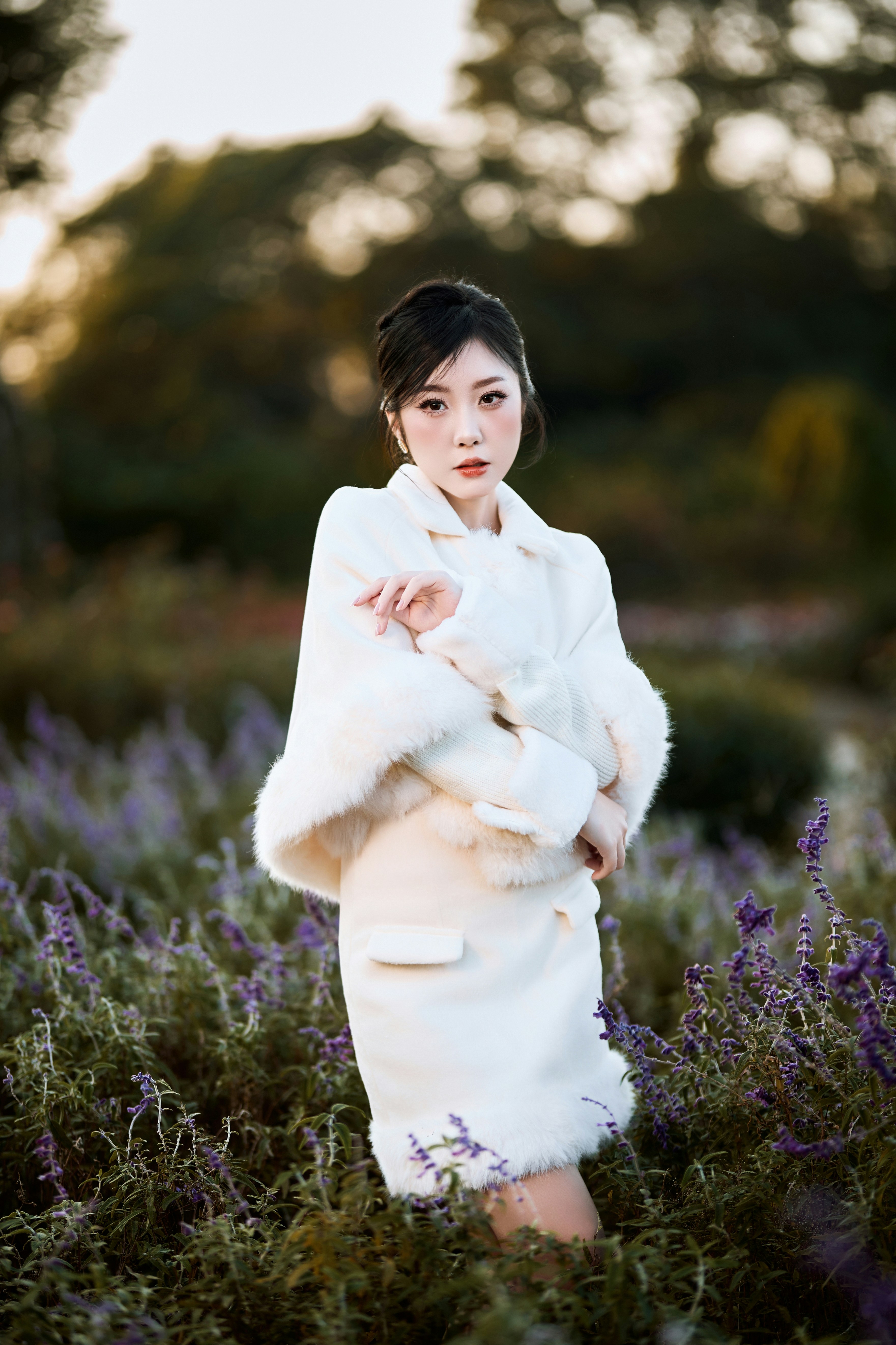 Woman in white coat standing in a field of lavender.