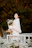 Woman in white coat holding bouquet of white flowers