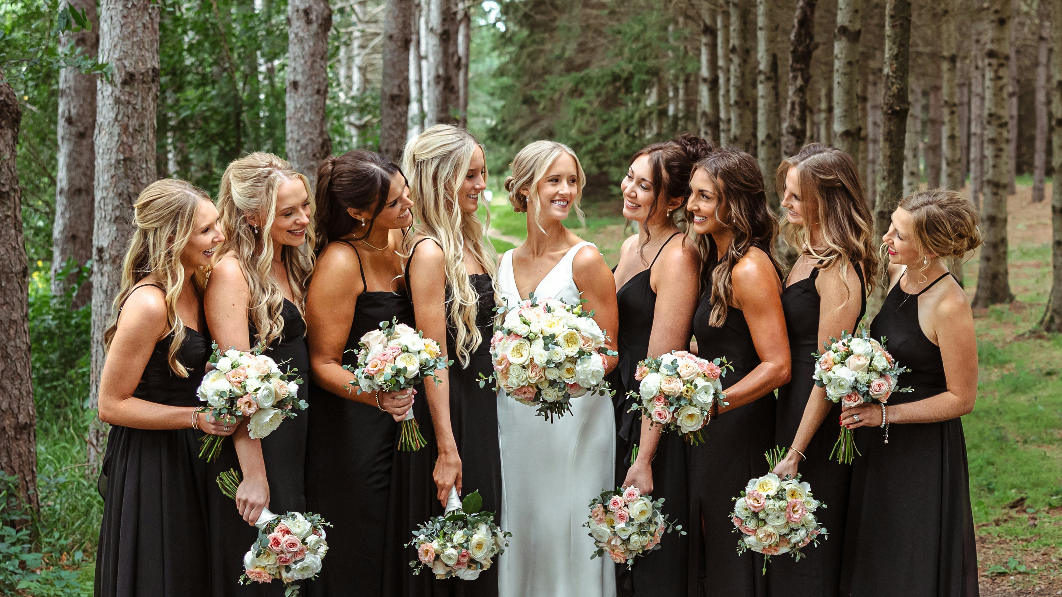Bride and bridesmaids holding bouquets in a forest