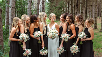 Bride and bridesmaids holding bouquets in a forest