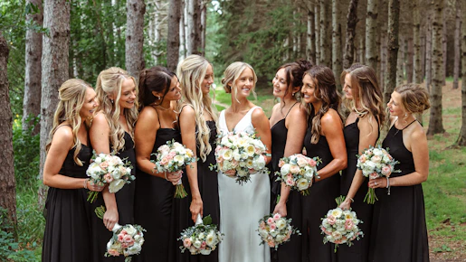 Bride and bridesmaids holding bouquets in a forest