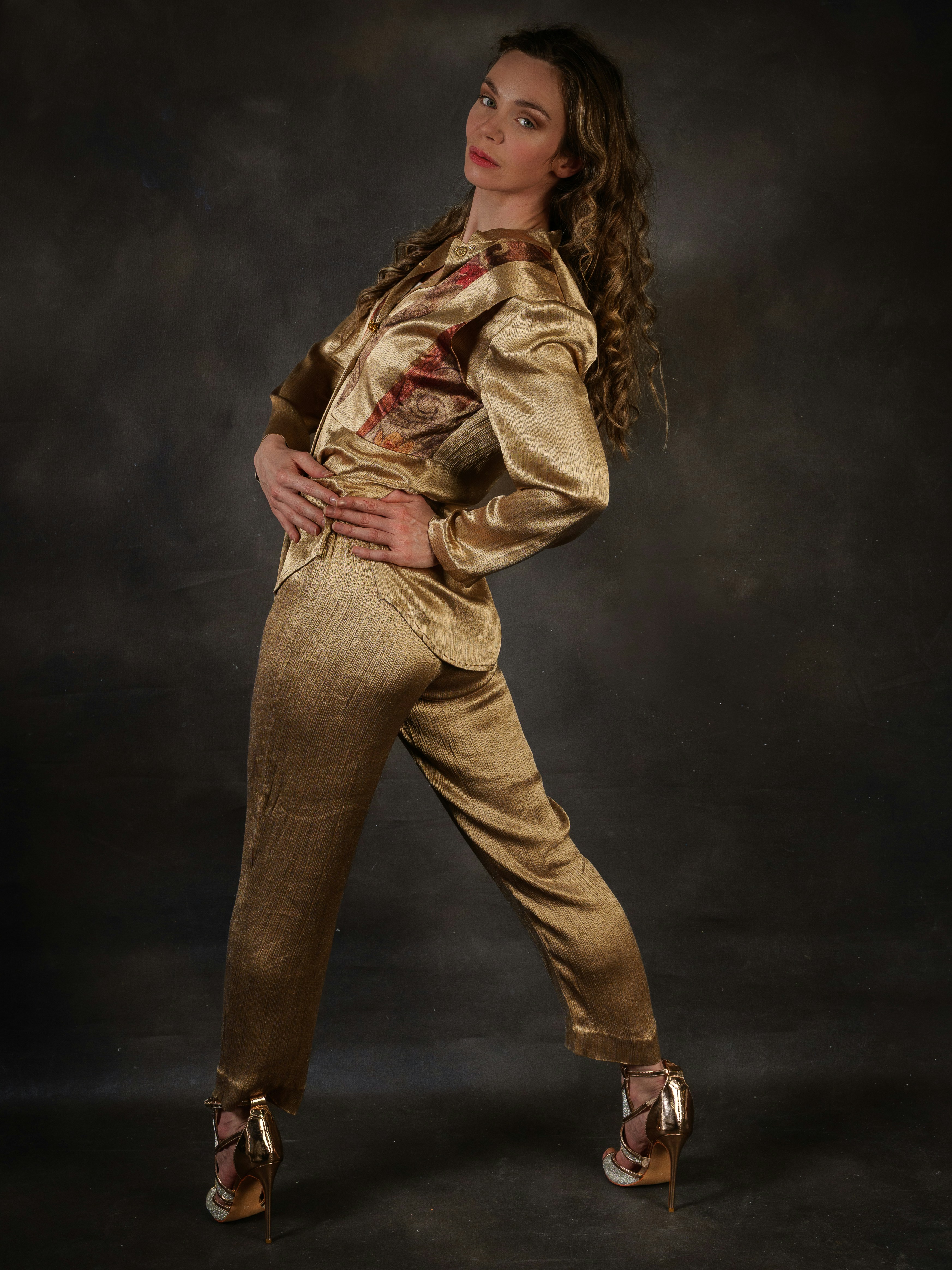 A woman poses in a shiny golden outfit.
