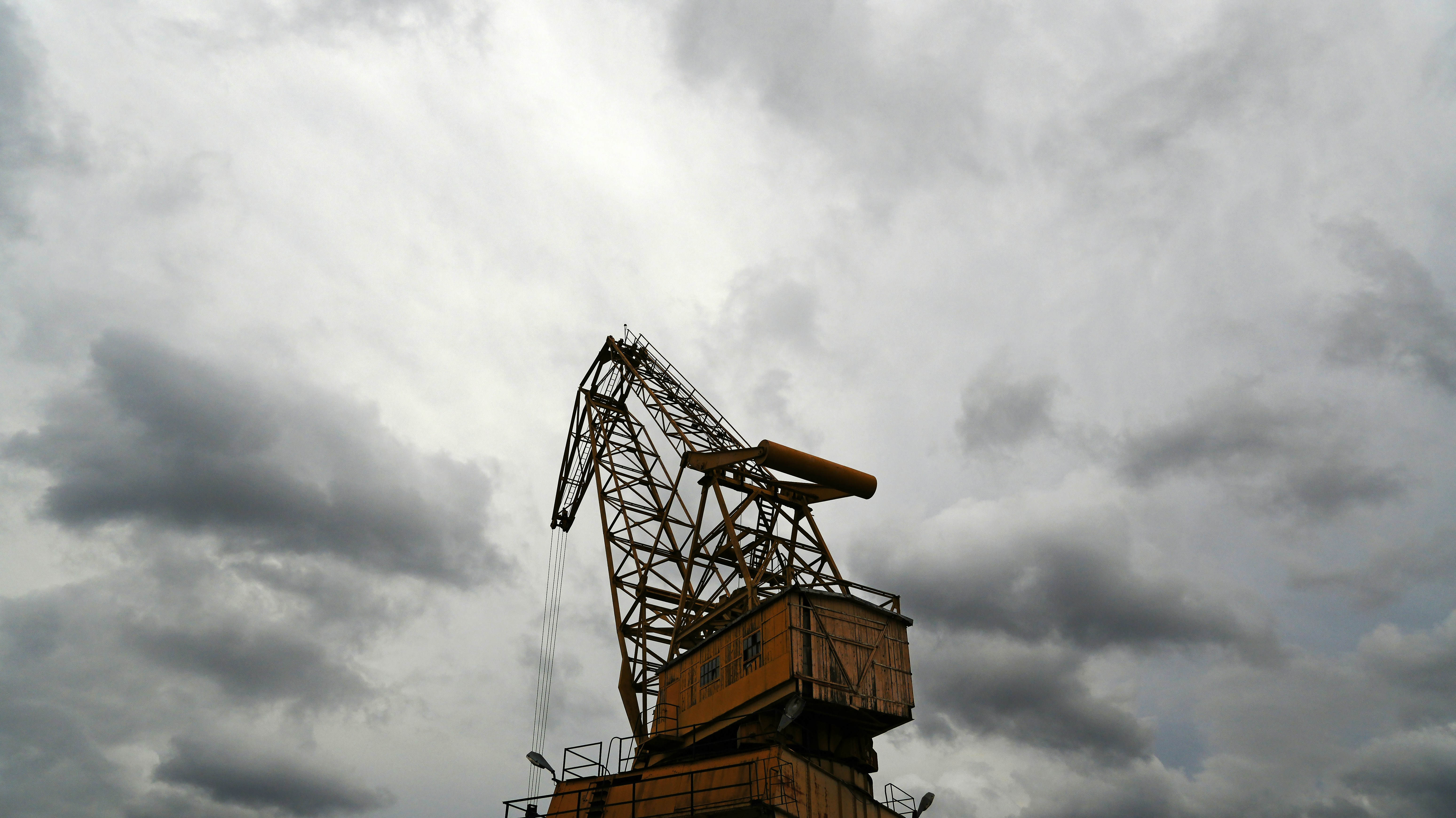 Une vieille grue industrielle sous un ciel nuageux.
