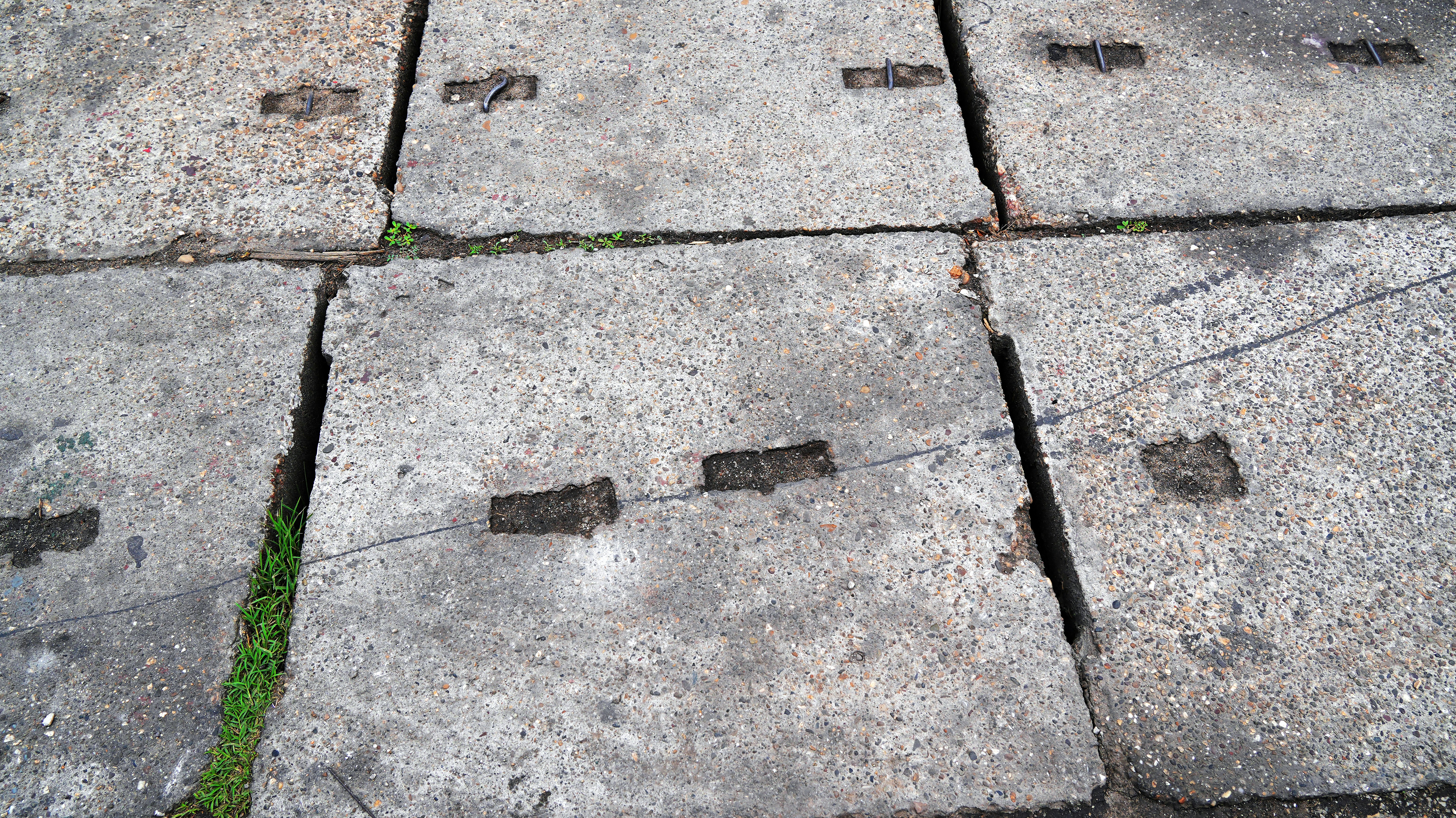 Des dalles de béton fissurées avec de l’herbe qui pousse entre elles