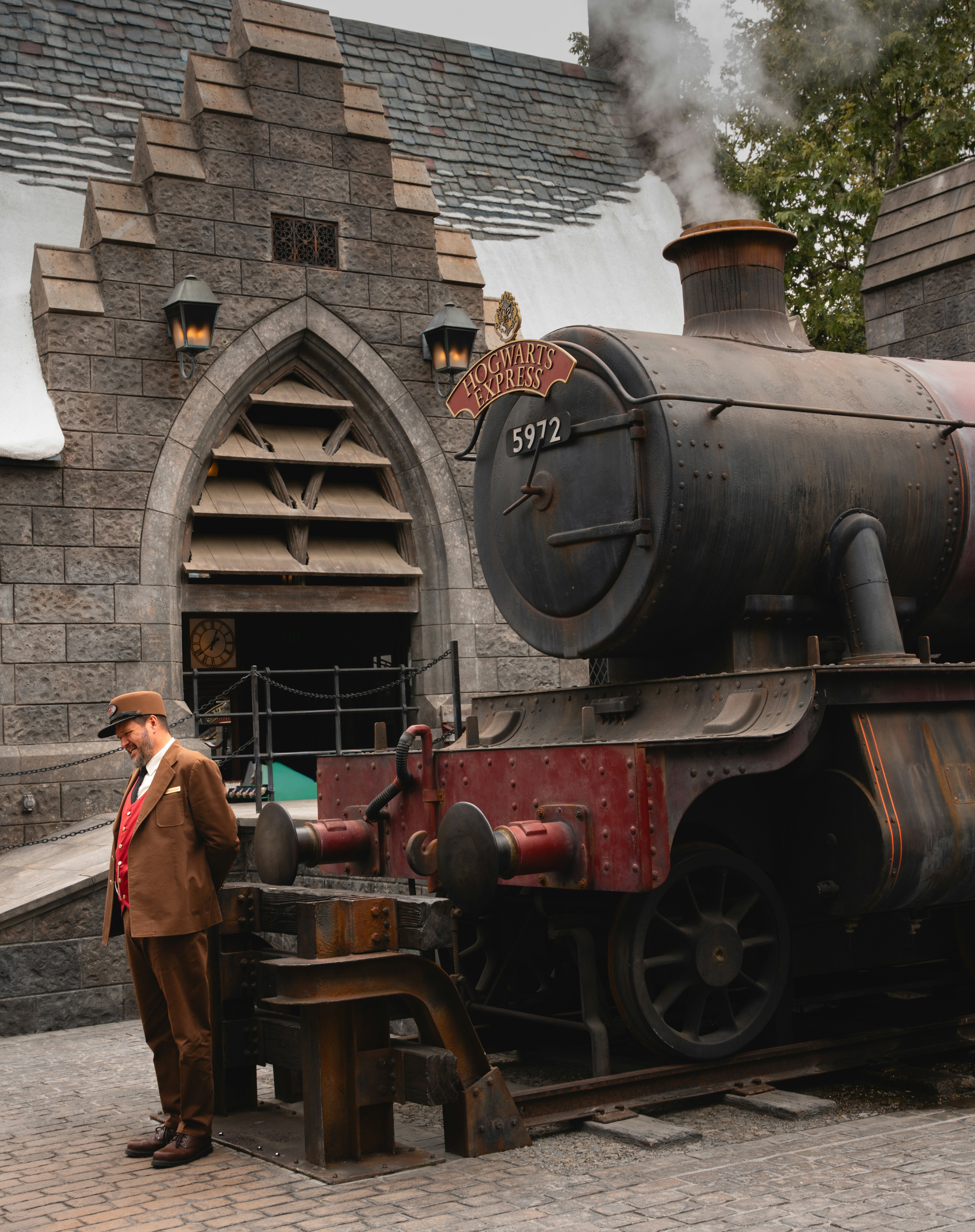 Un homme en costume se tient près d’un train à vapeur.