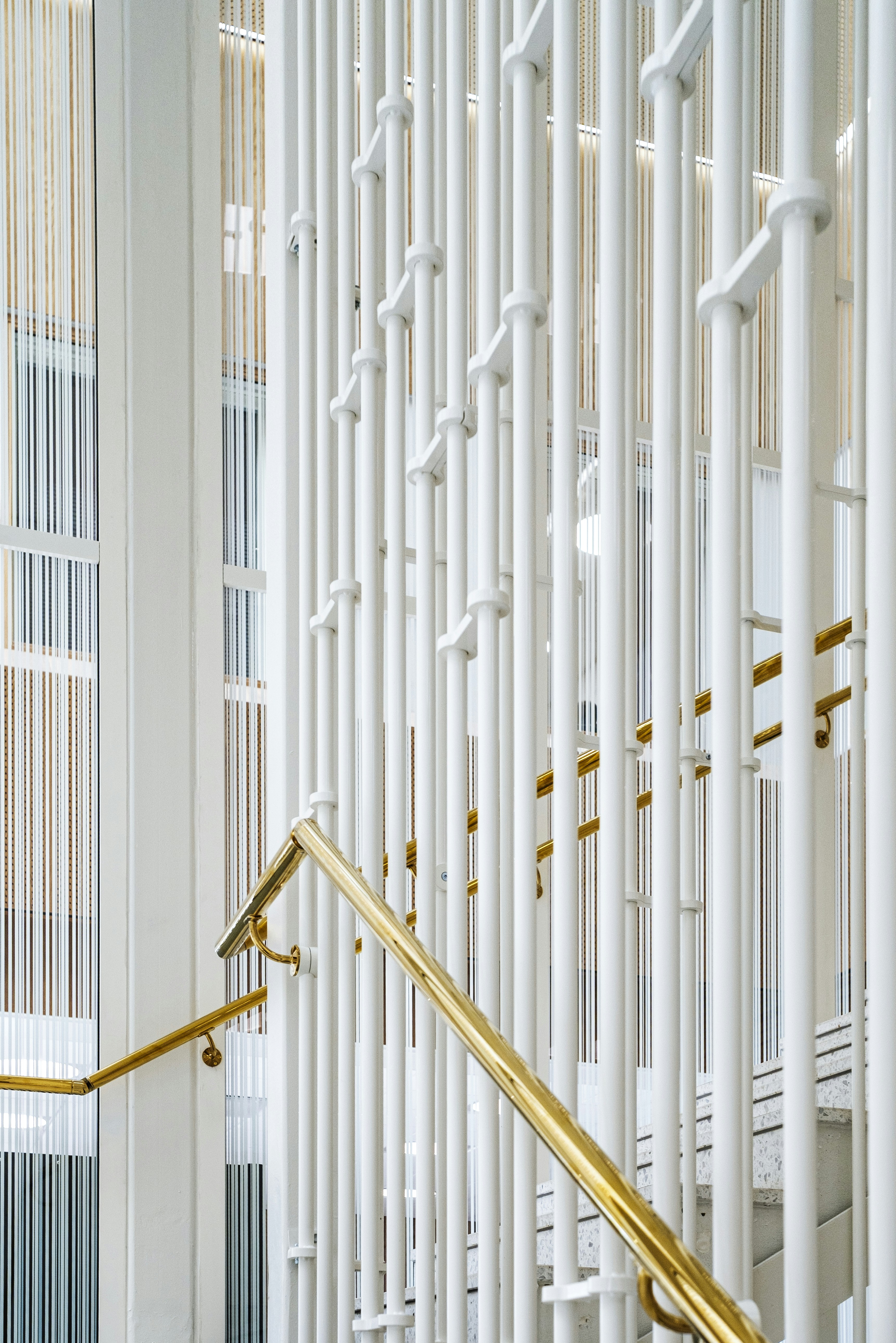 Modern staircase with white railings and brass handrail