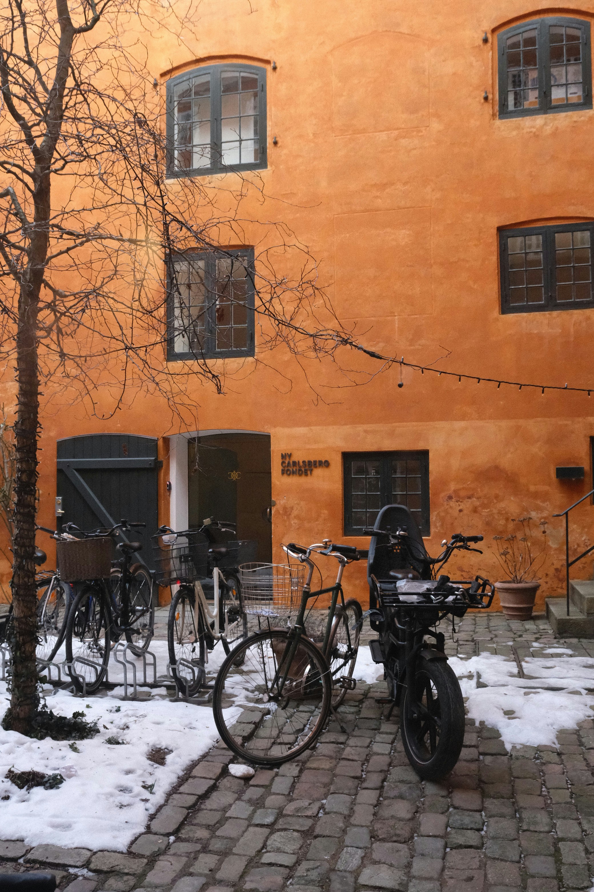 Fahrräder, die im Winter vor einem orangefarbenen Gebäude parken