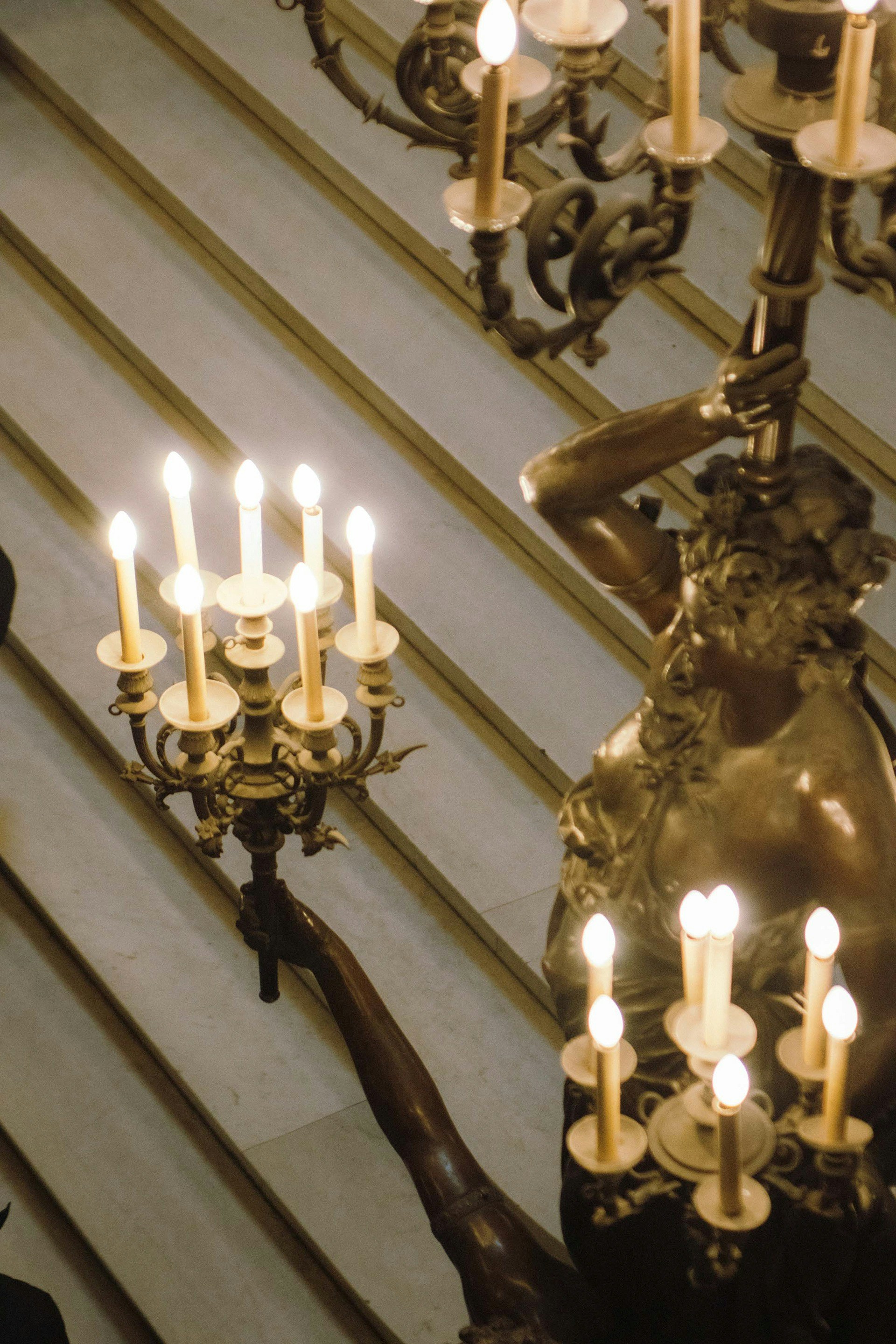 Candelabros ornamentados com velas acesas em uma escada.