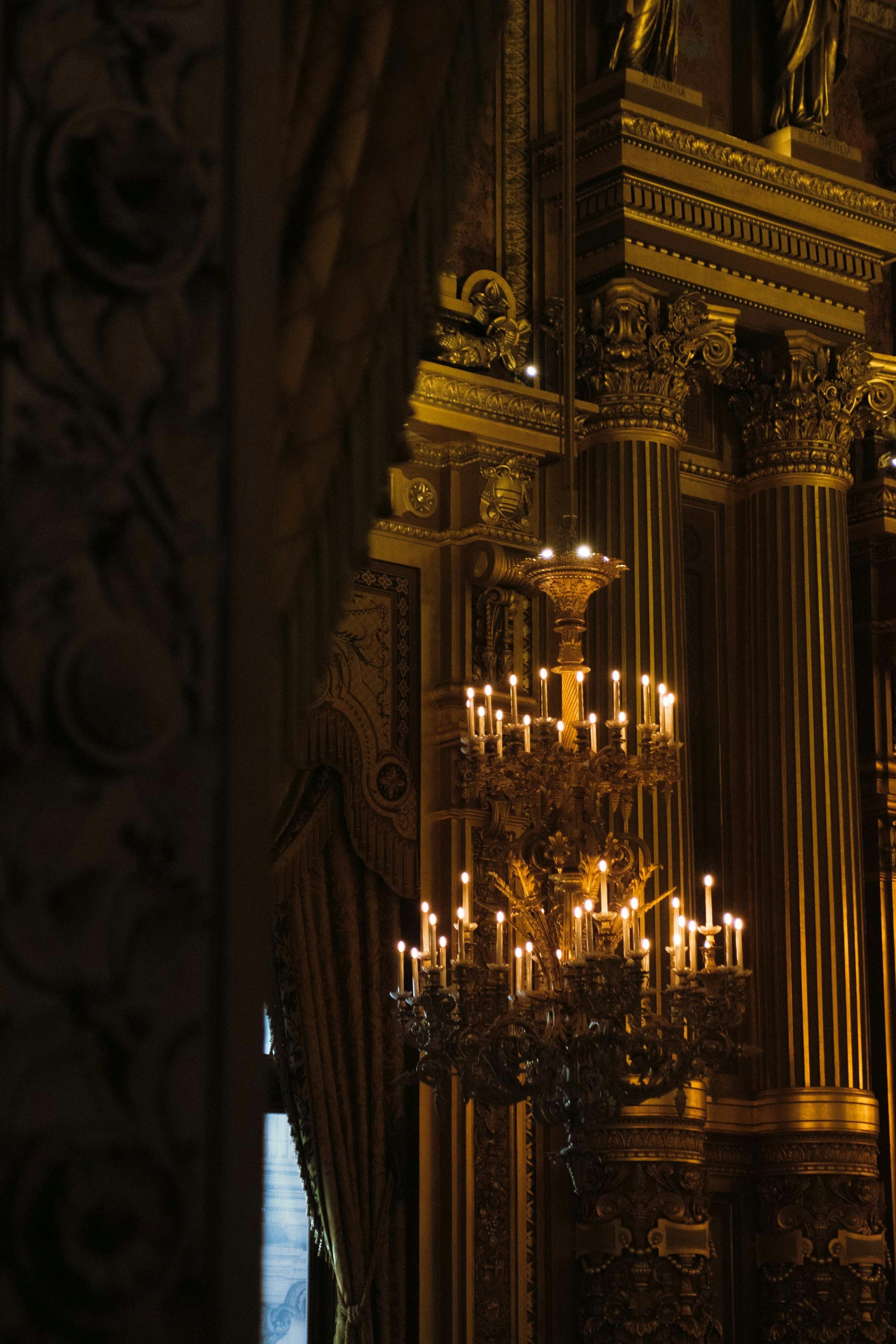 Lustre ornamentado com velas acesas em um grande salão