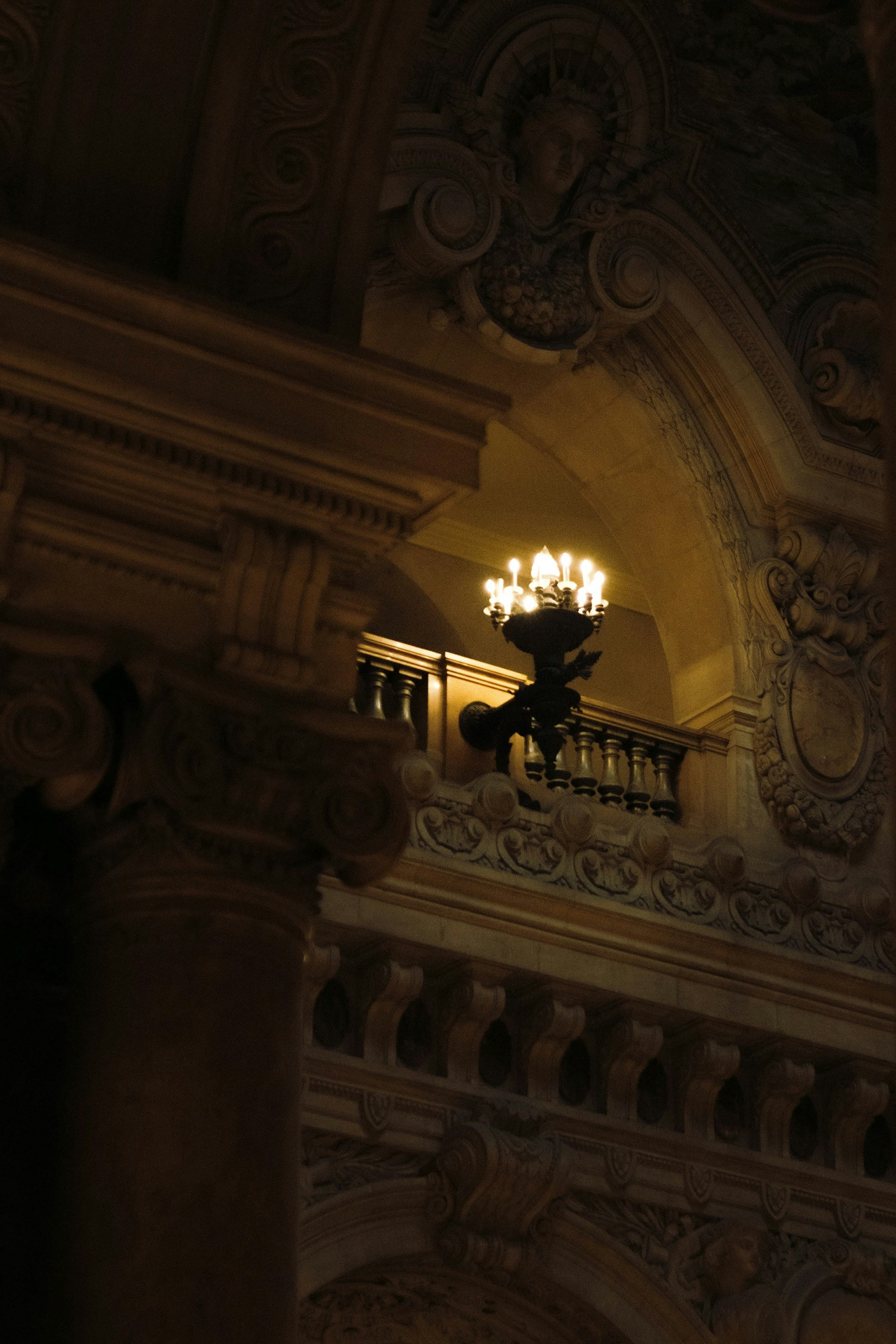 Lustre ornamentado ilumina uma varanda em um interior grandioso