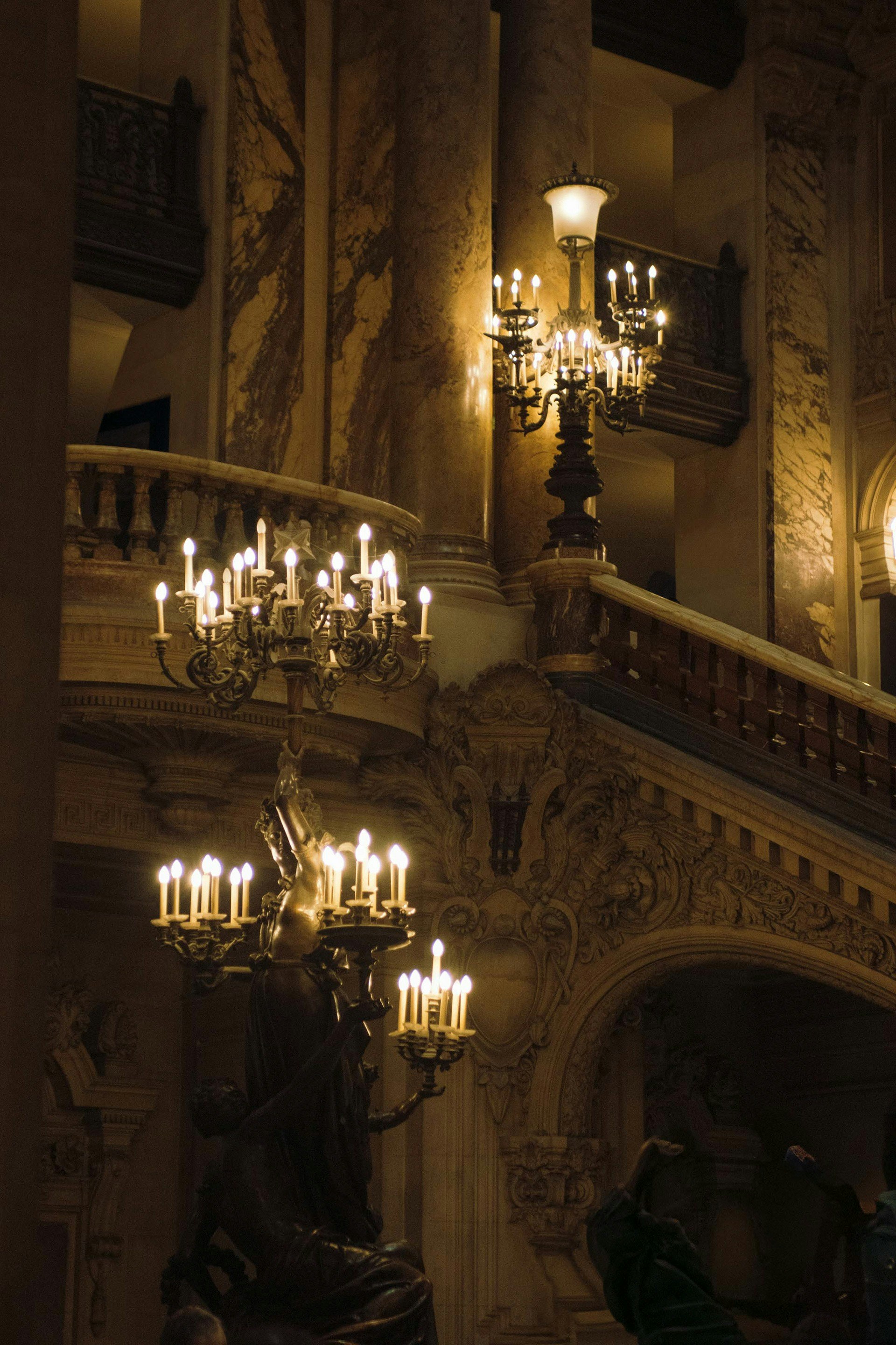 Candelabros ornamentados iluminam uma grande escadaria de mármore