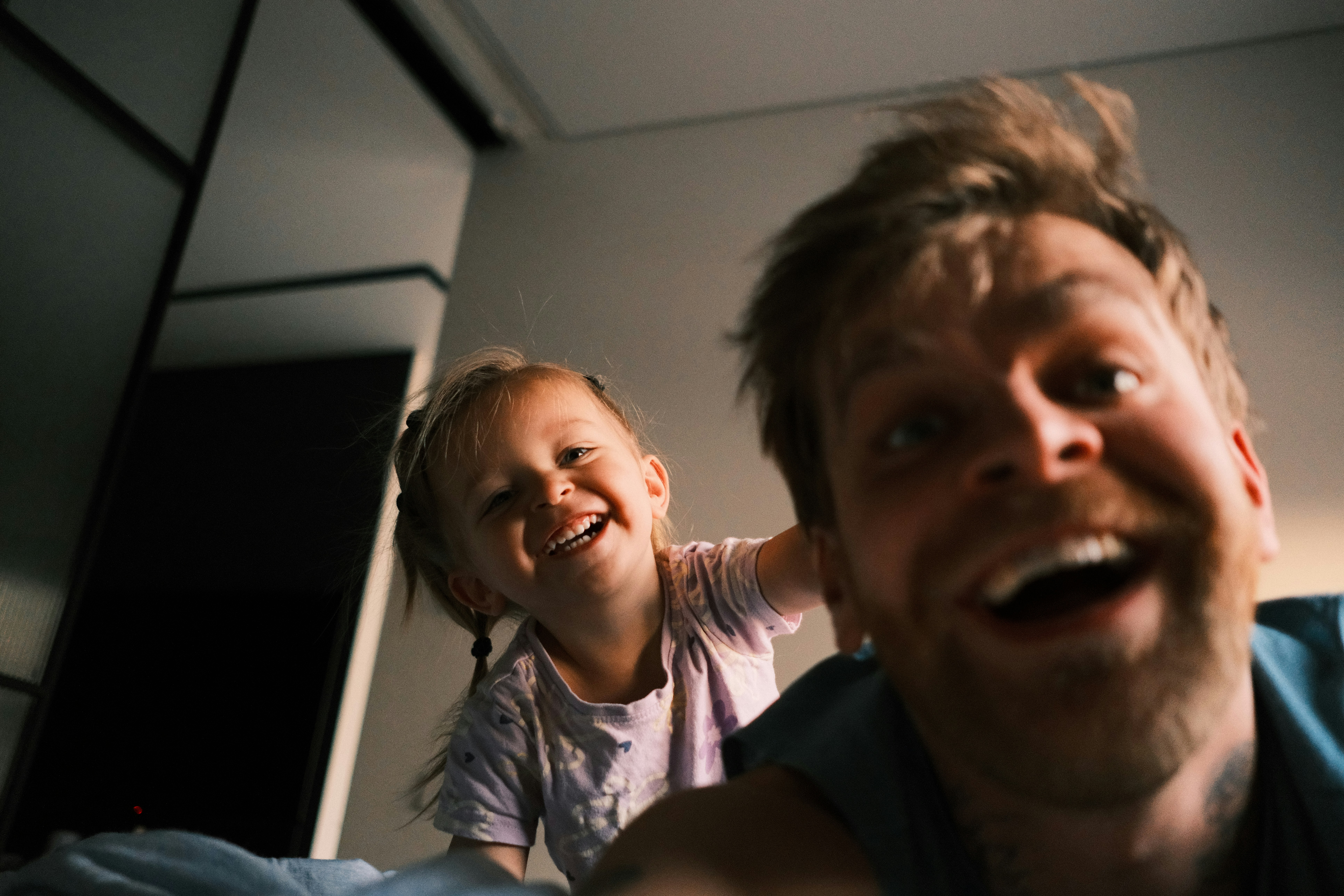 Father and daughter laughing together in bed.