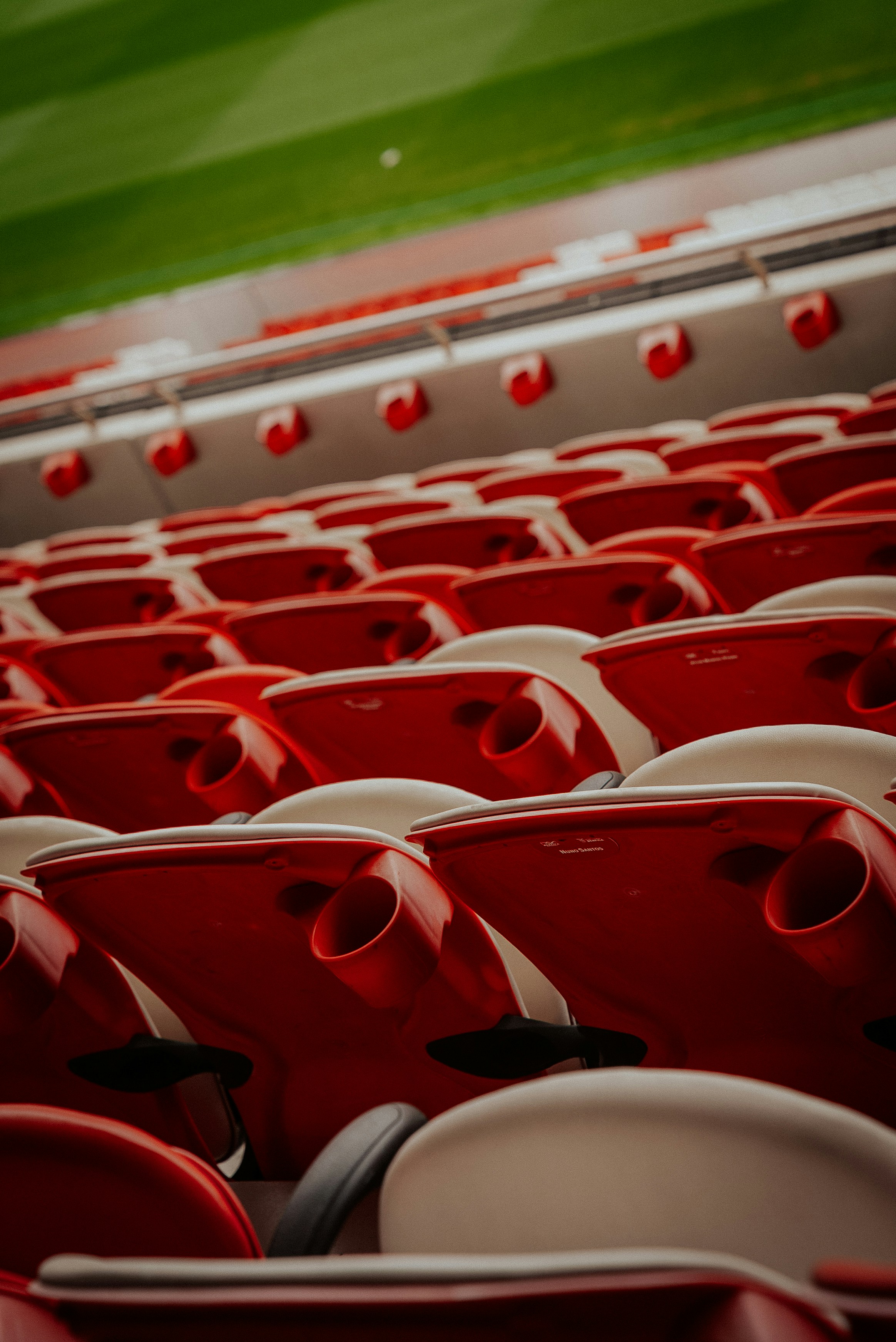 Sièges rouges vides dans le stade avec terrain vert au-dessus.