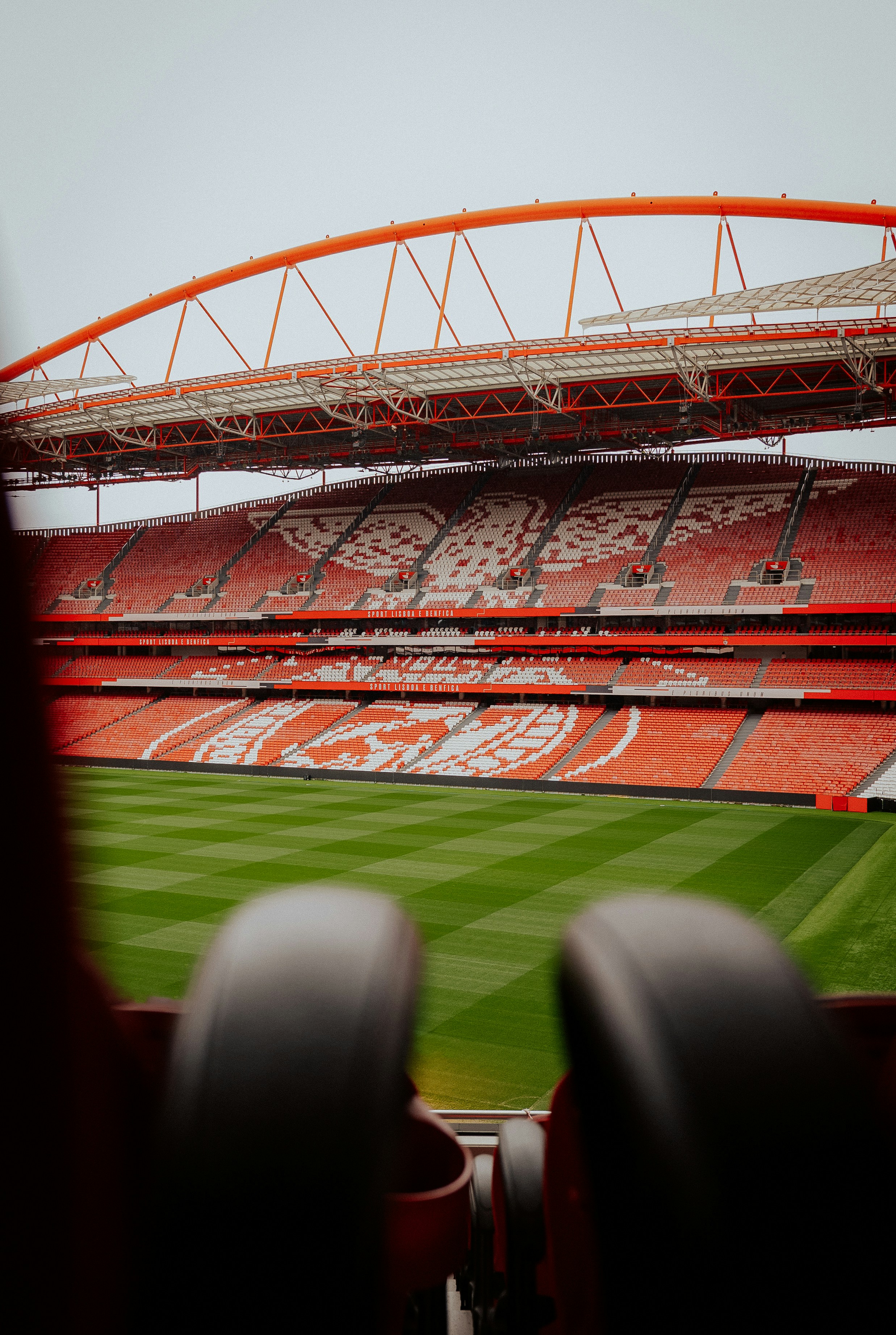 Stade vide avec des sièges rouges et un terrain vert.