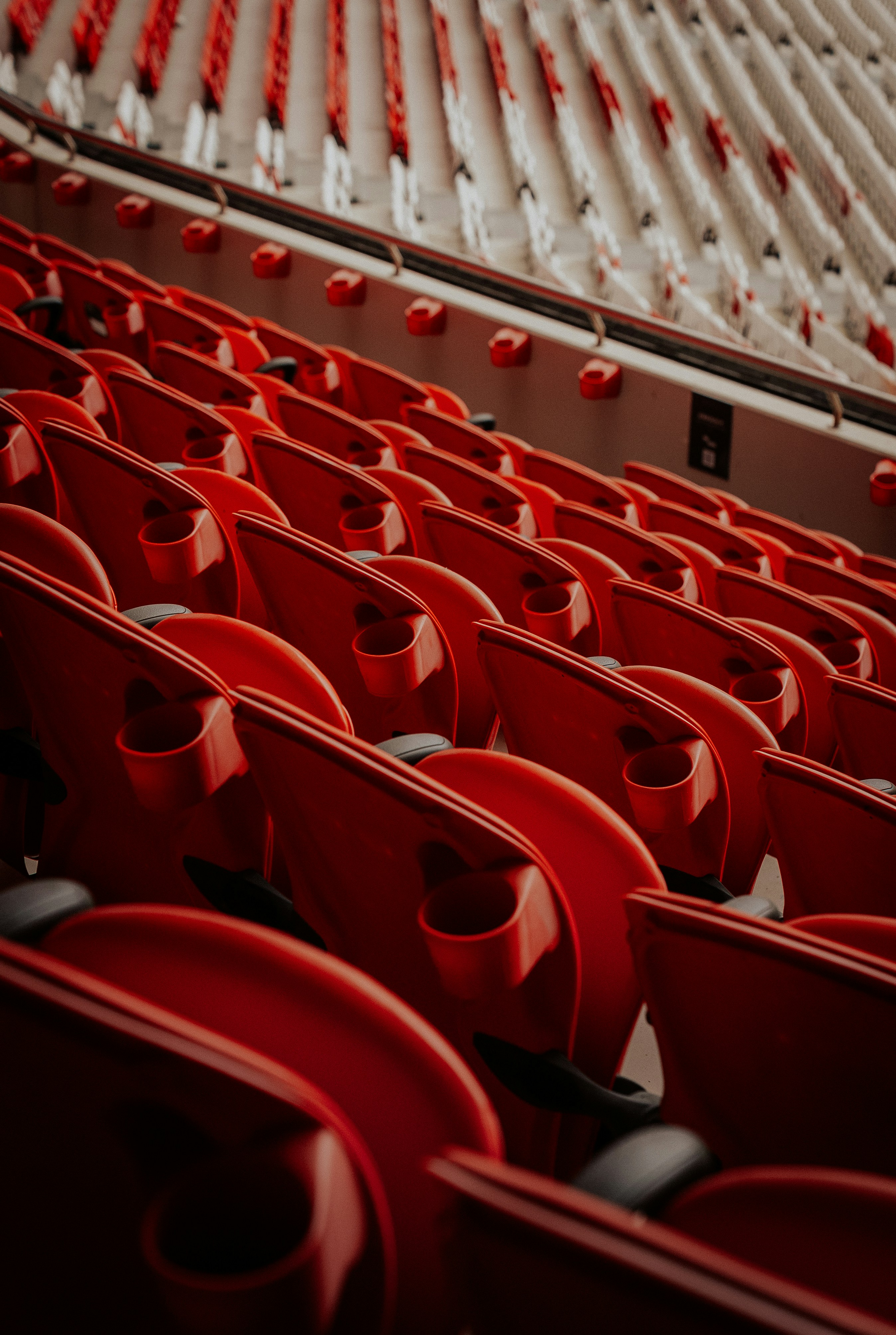 Rows of empty red stadium seats under bright lights