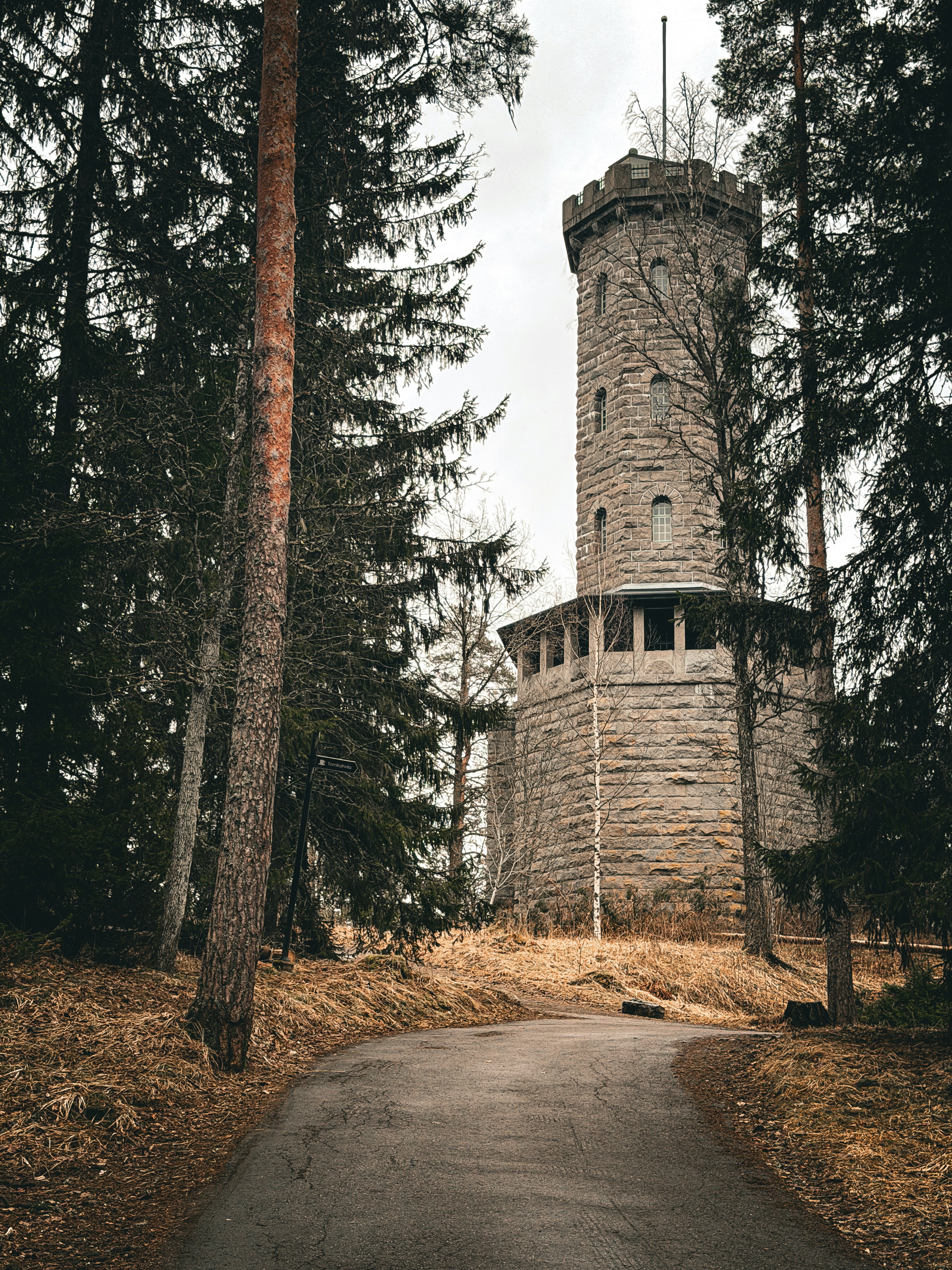 Steinturm in einem Wald mit einem gewundenen Pfad.