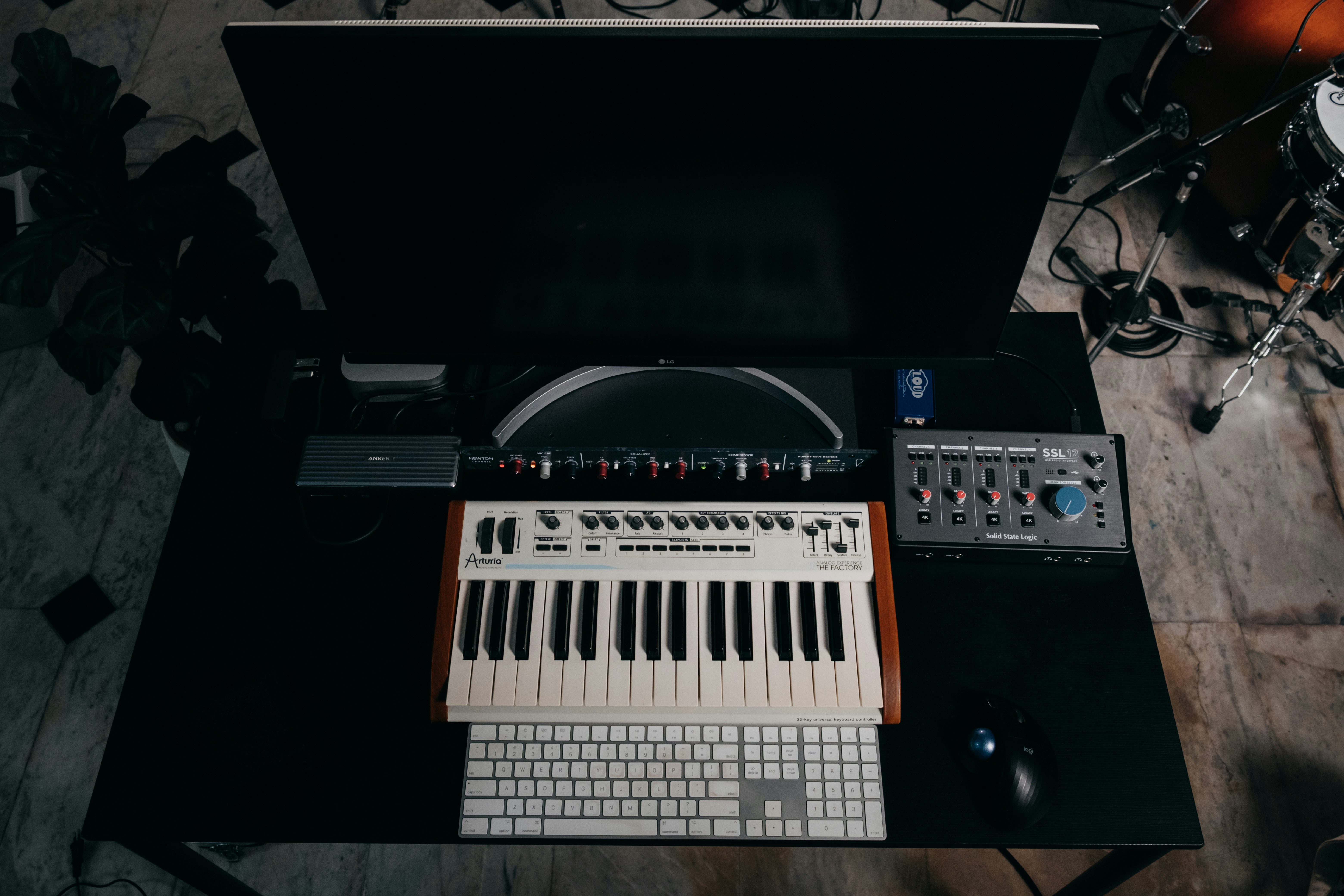 A desk with a keyboard, synthesizer, and audio equipment.