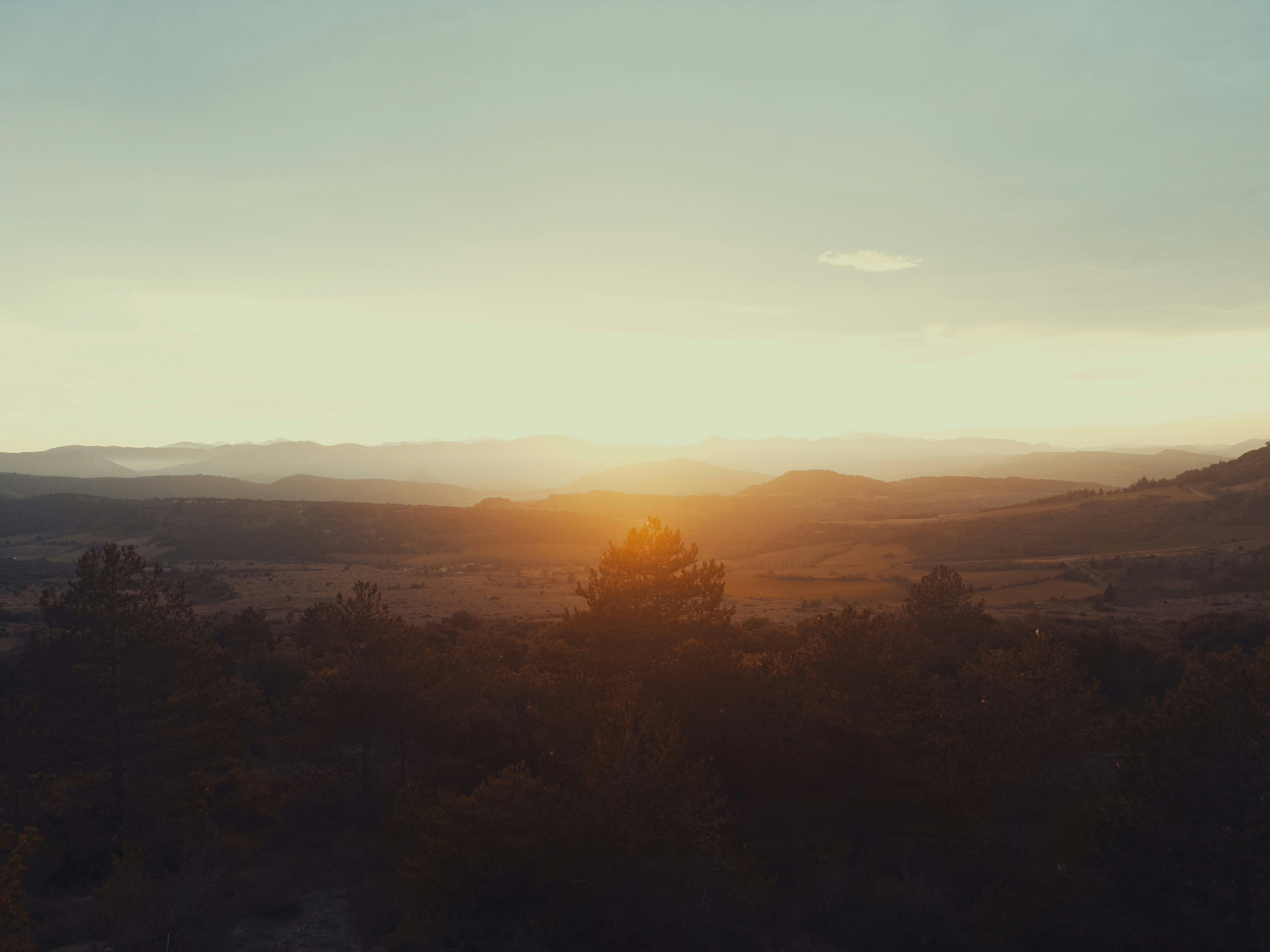 Sonnenaufgang über einer weiten, nebligen Berglandschaft.