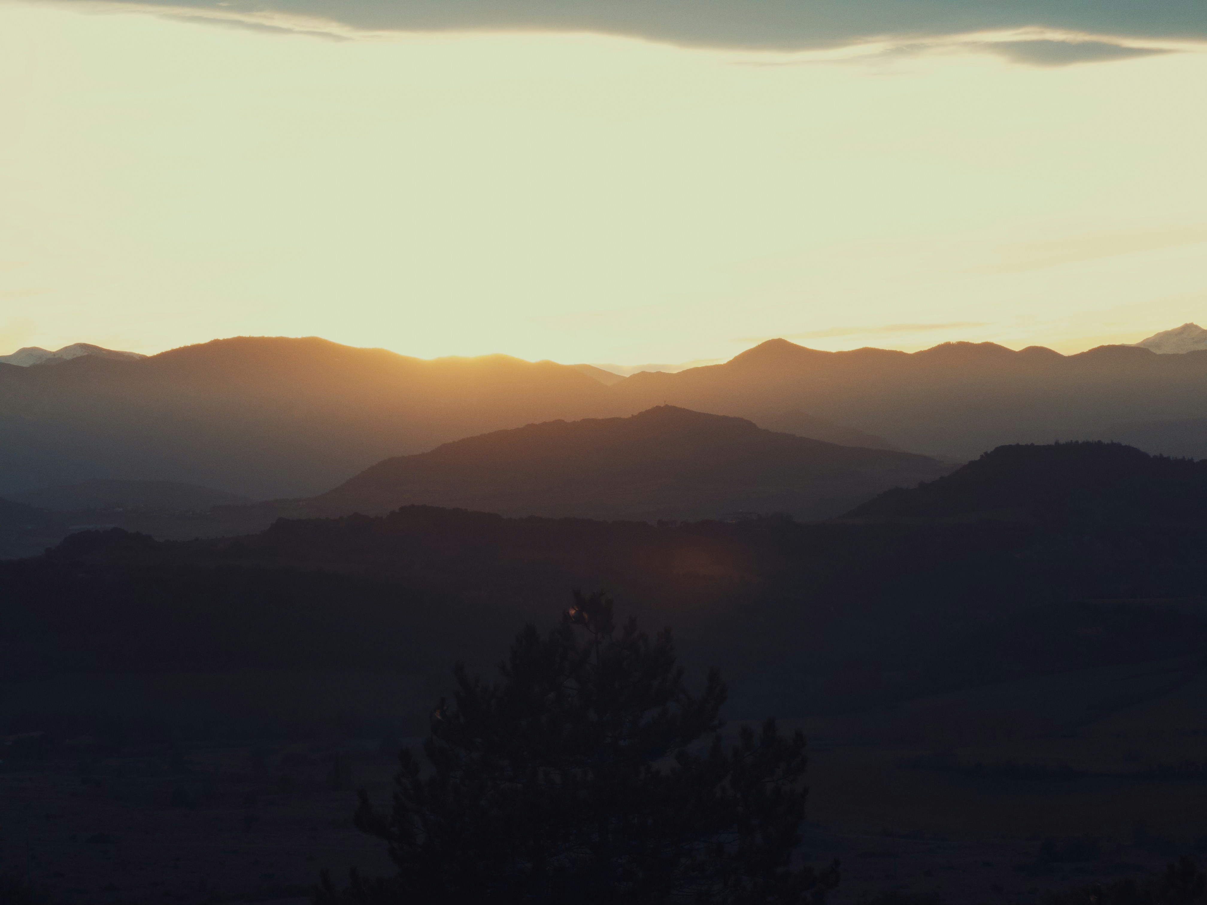Sonnenuntergang über geschichteten Gebirgszügen bei Einbruch der Dämmerung