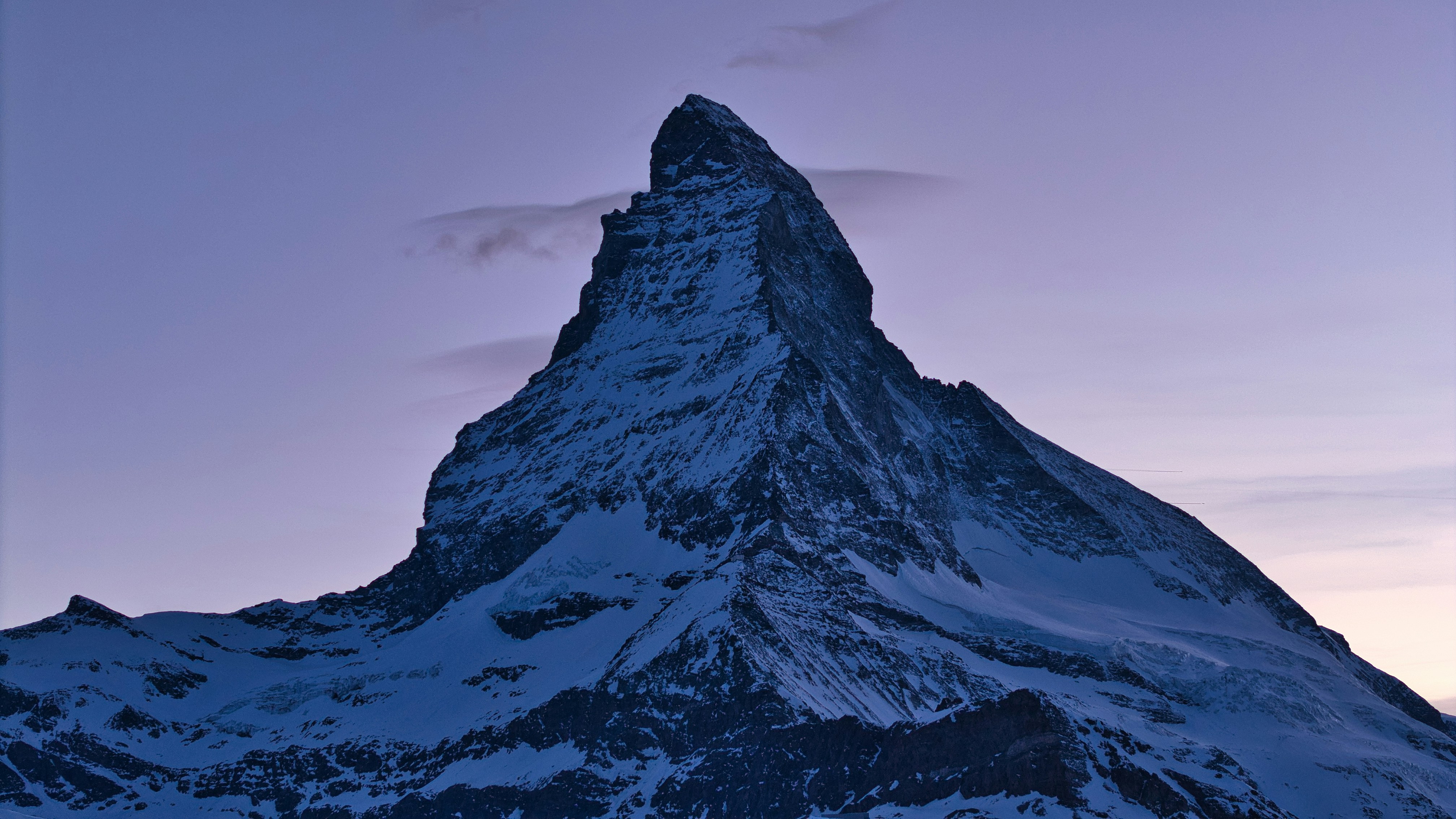 Snowy mountain peak against a purple twilight sky.