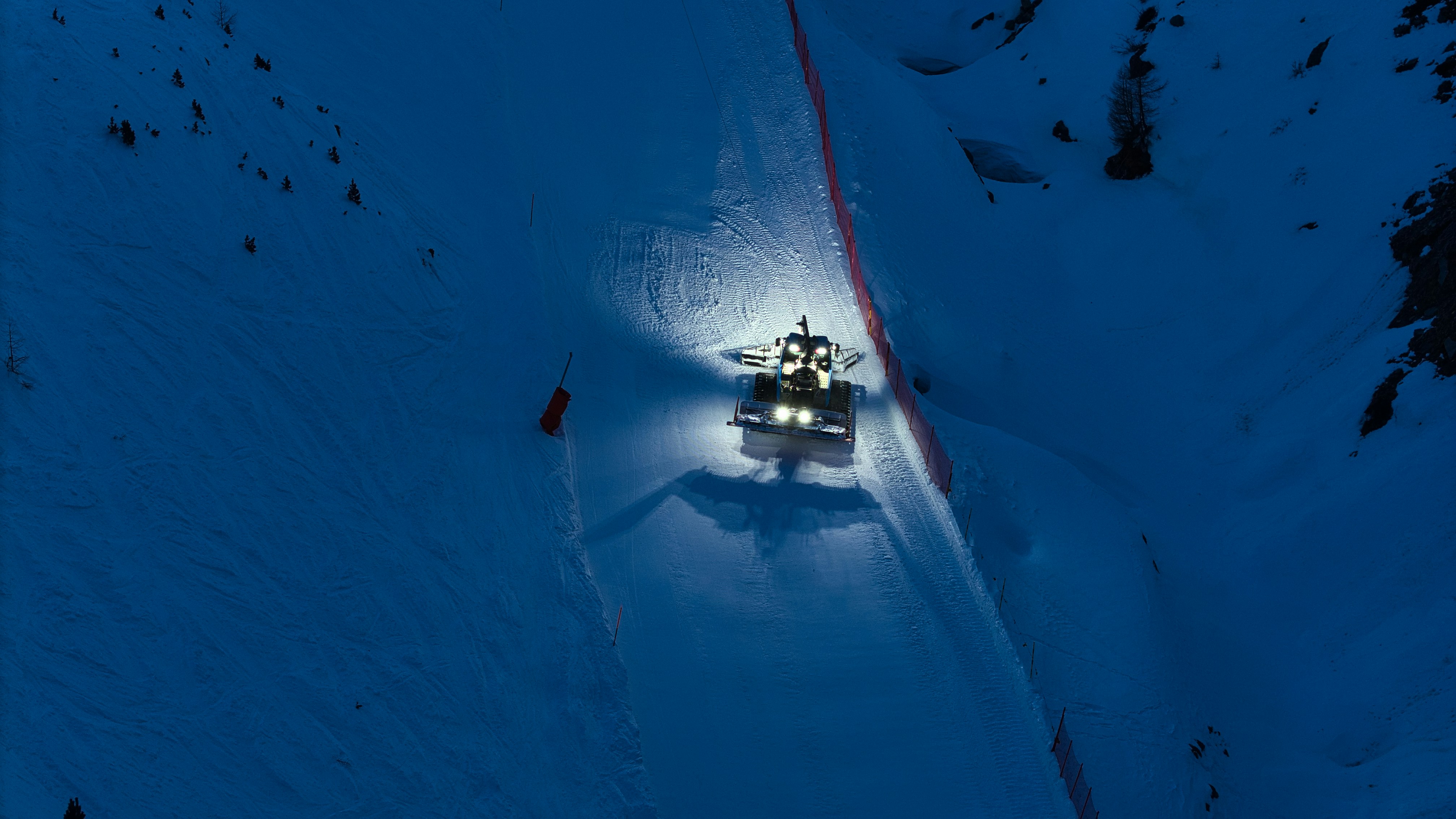 Snow groomer preparing a ski slope at night