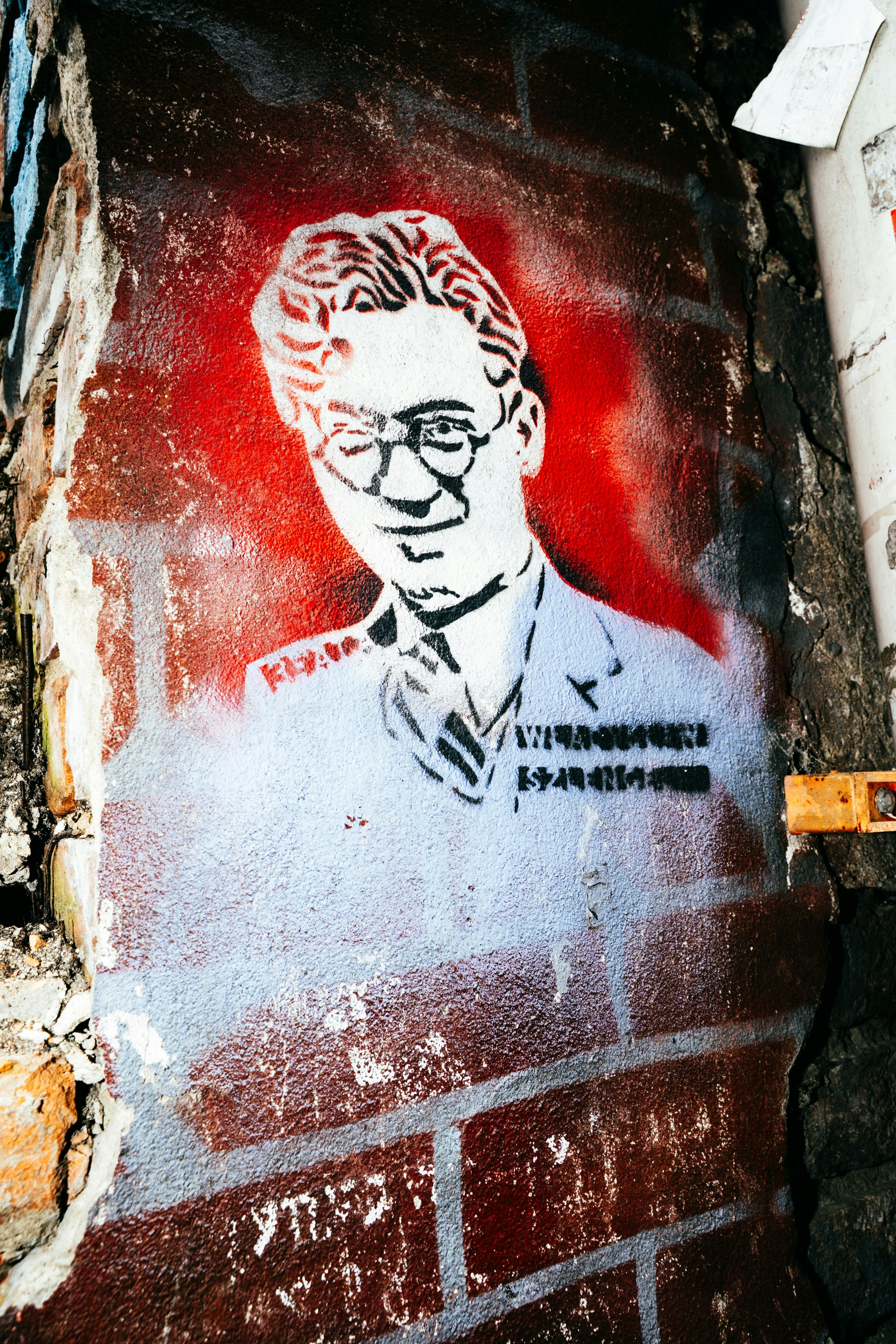 Retrato estêncil de um homem de óculos na parede de tijolos