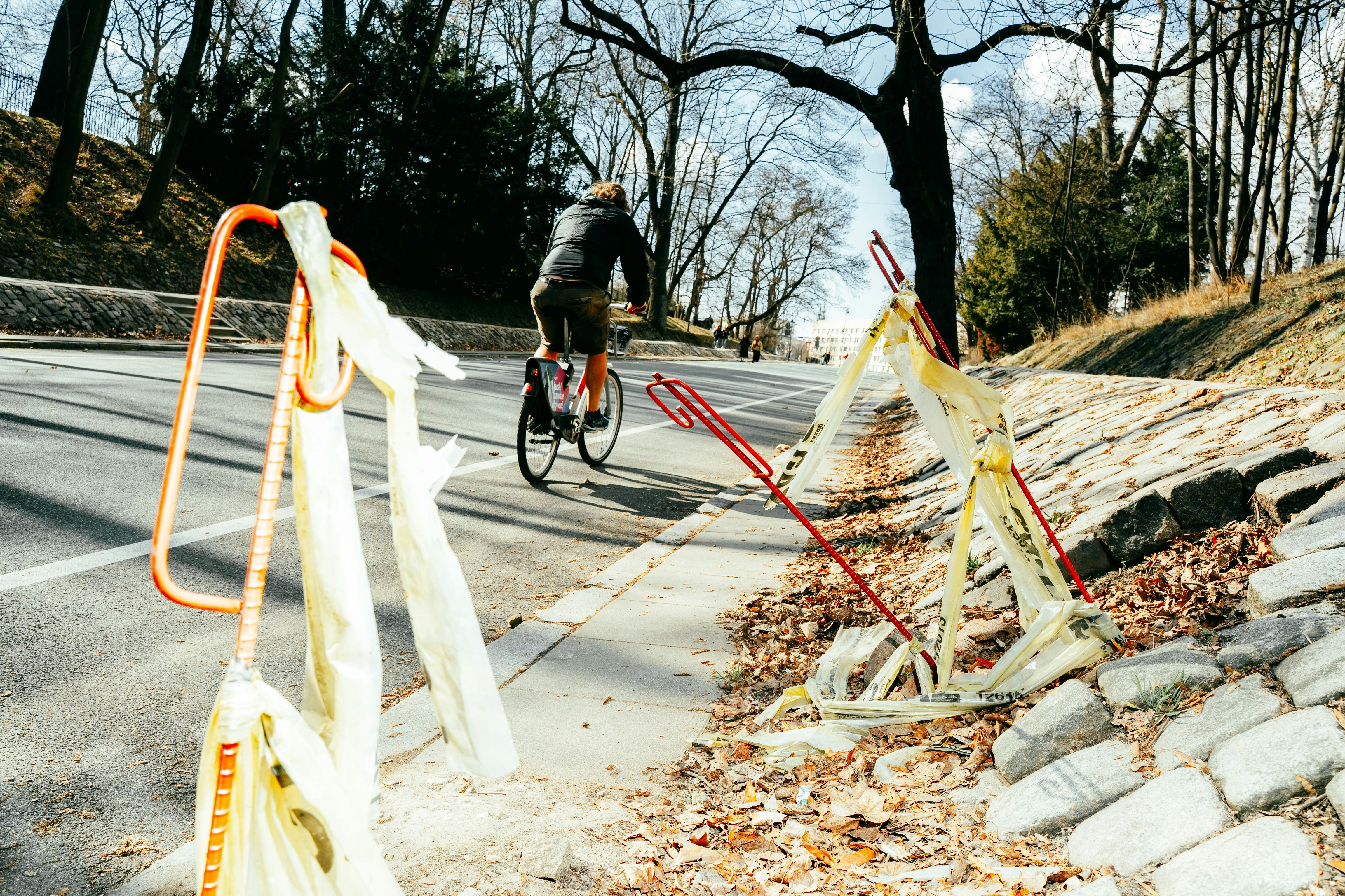 Cyclist rides up a tree-lined road with caution tape.