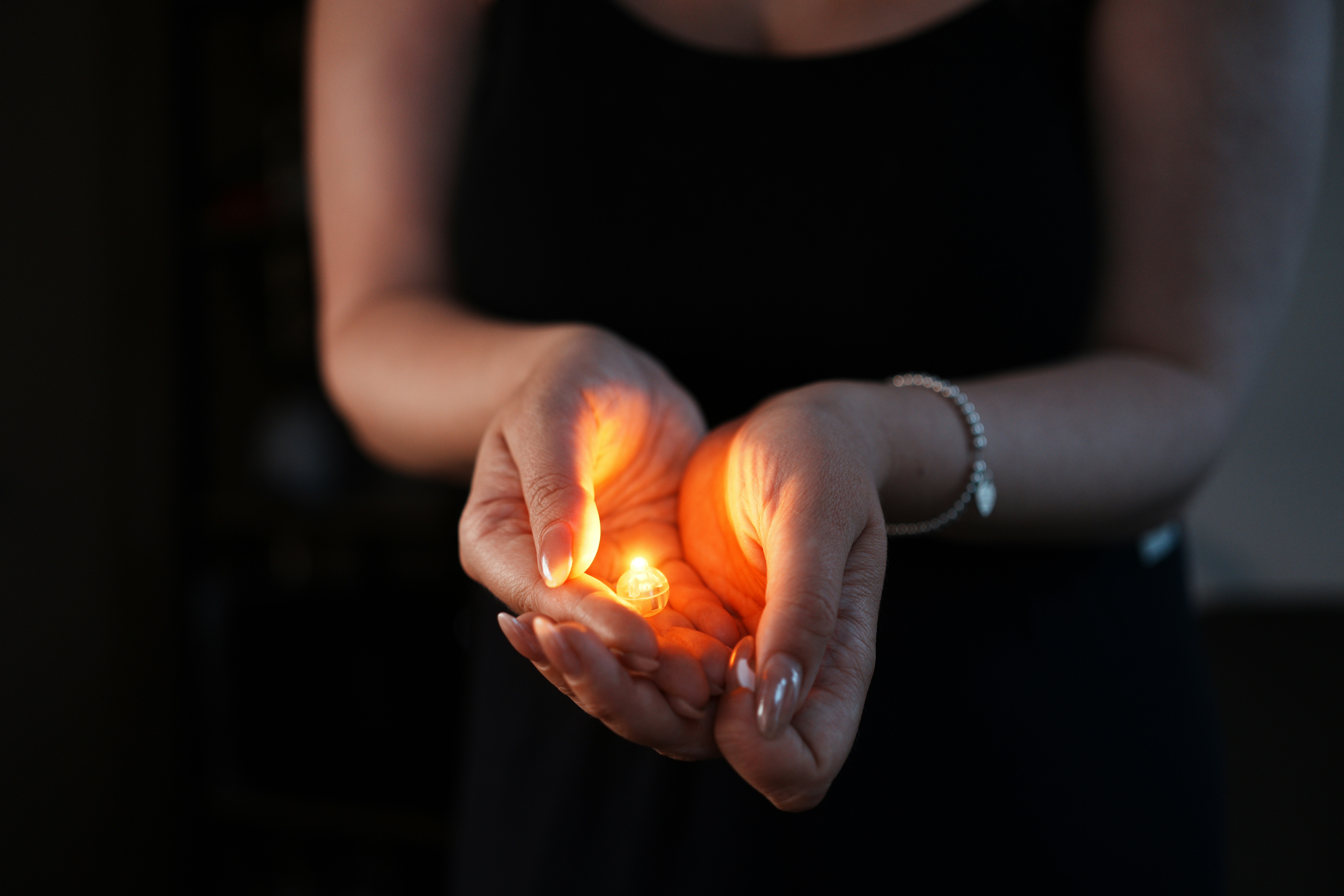Woman holding glowing embers in cupped hands