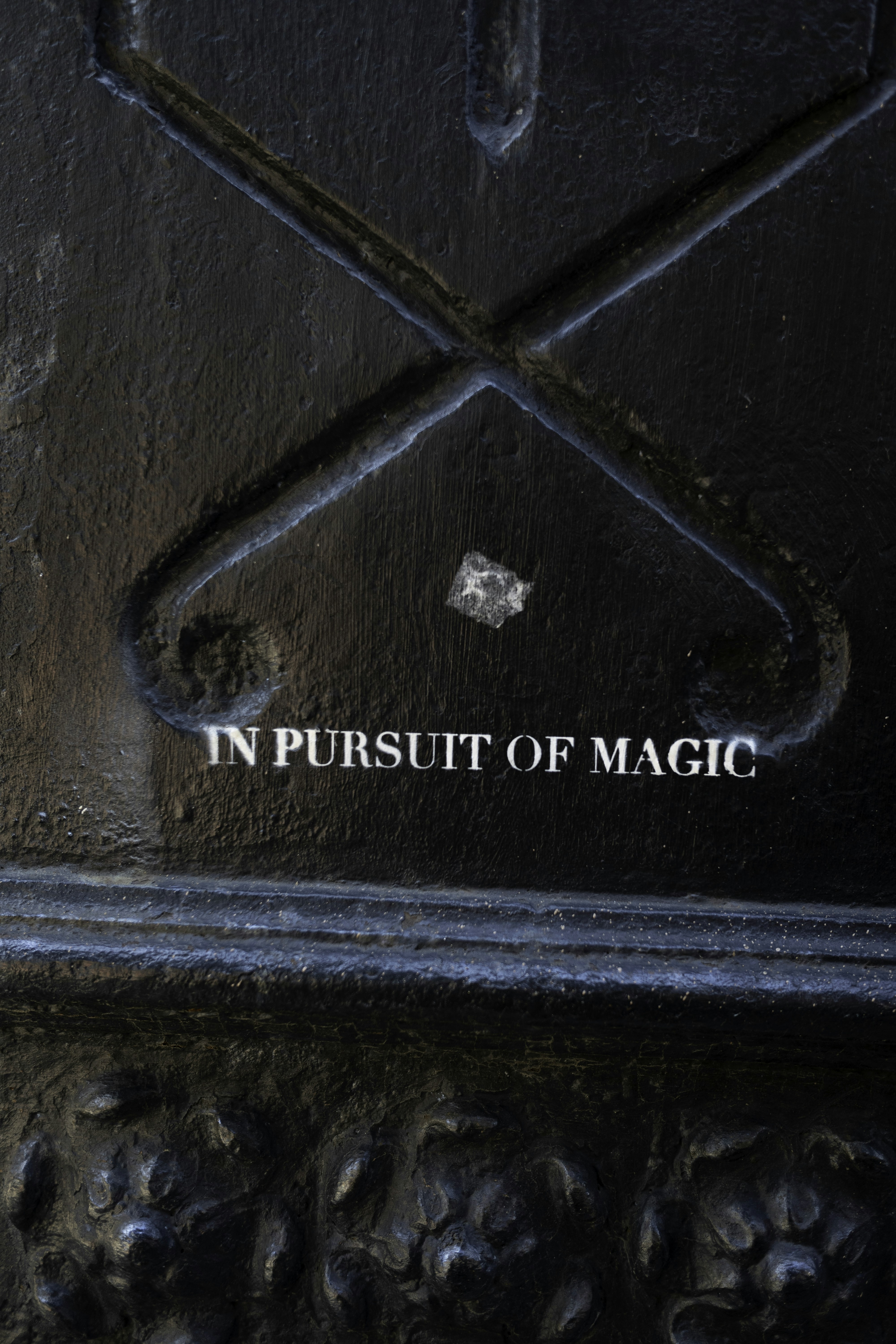 Text reads "in pursuit of magic" on dark metal