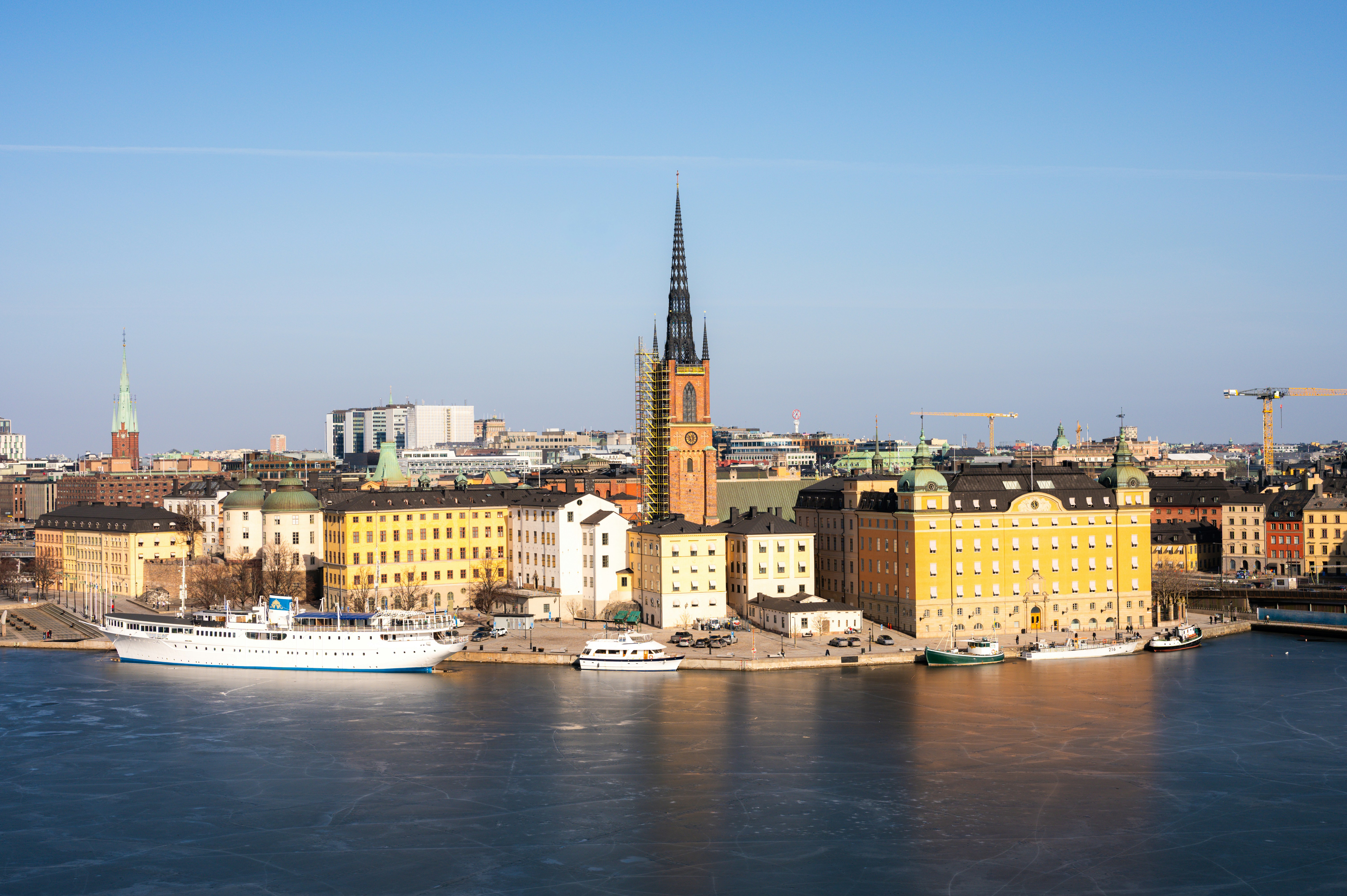 City skyline with historic buildings and a large white ship.