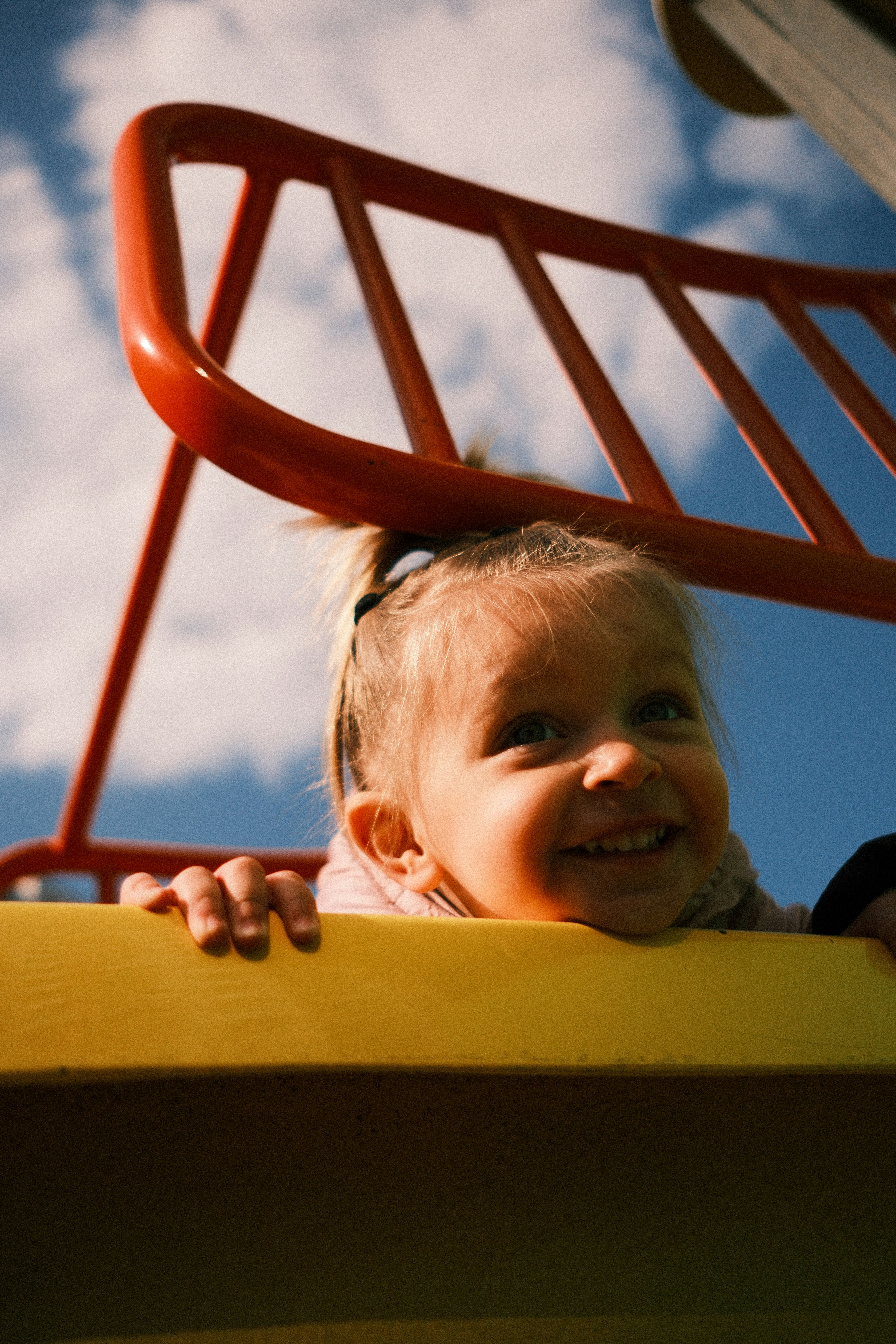 A smiling young girl on a playground structure