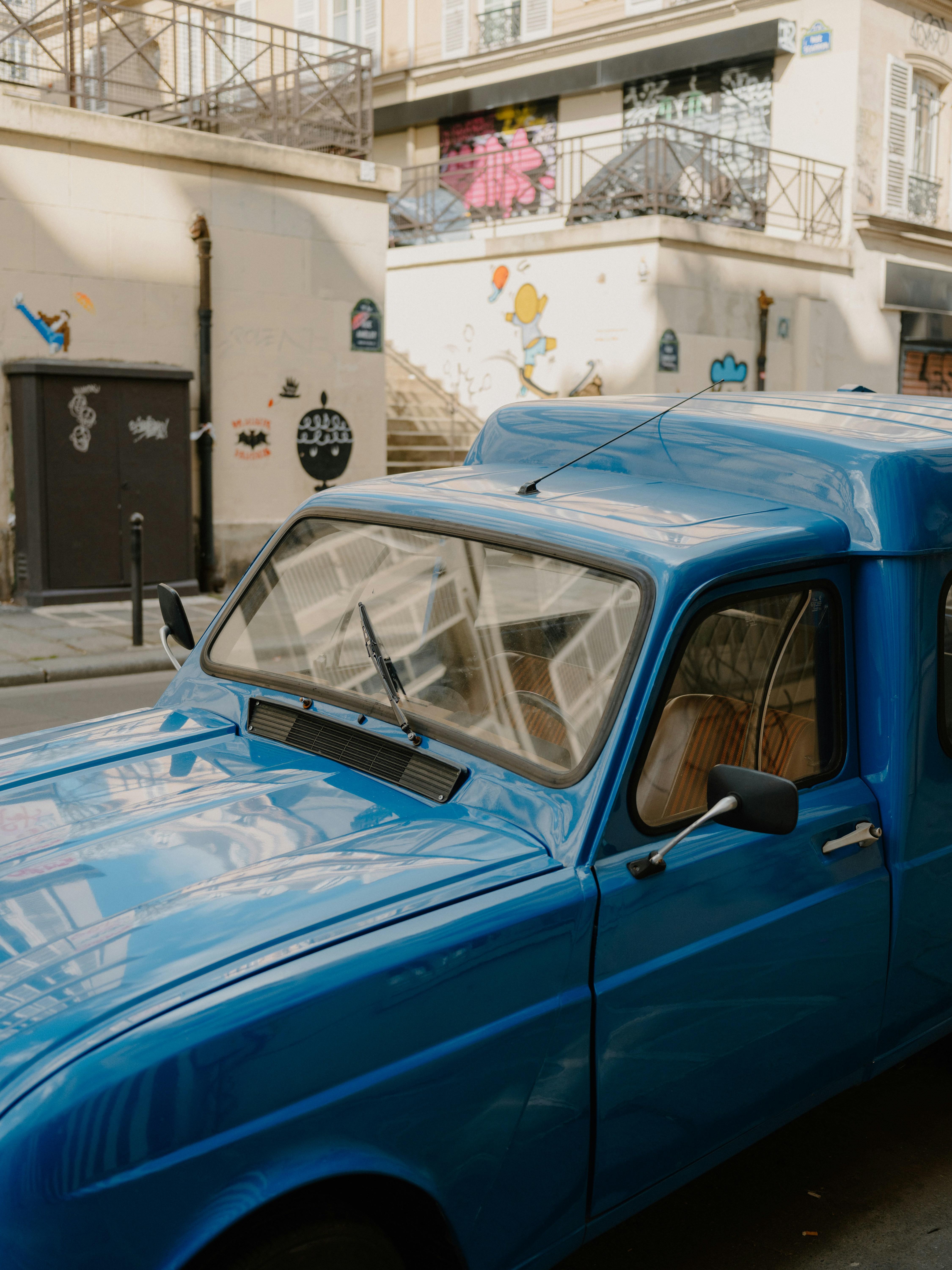 Uma van vintage azul brilhante estacionada numa rua.