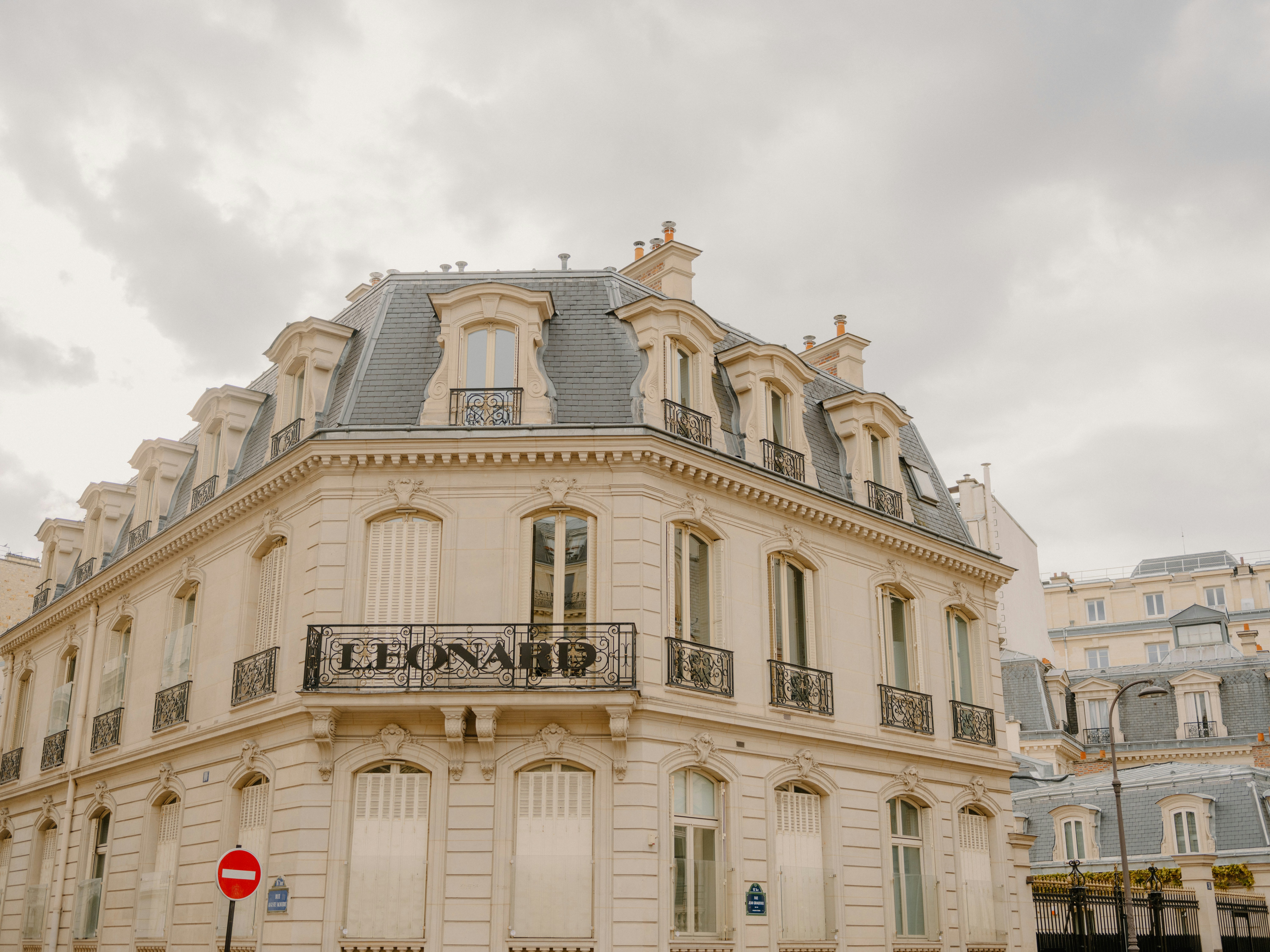 Ornate parisian building with mansard roof under cloudy sky