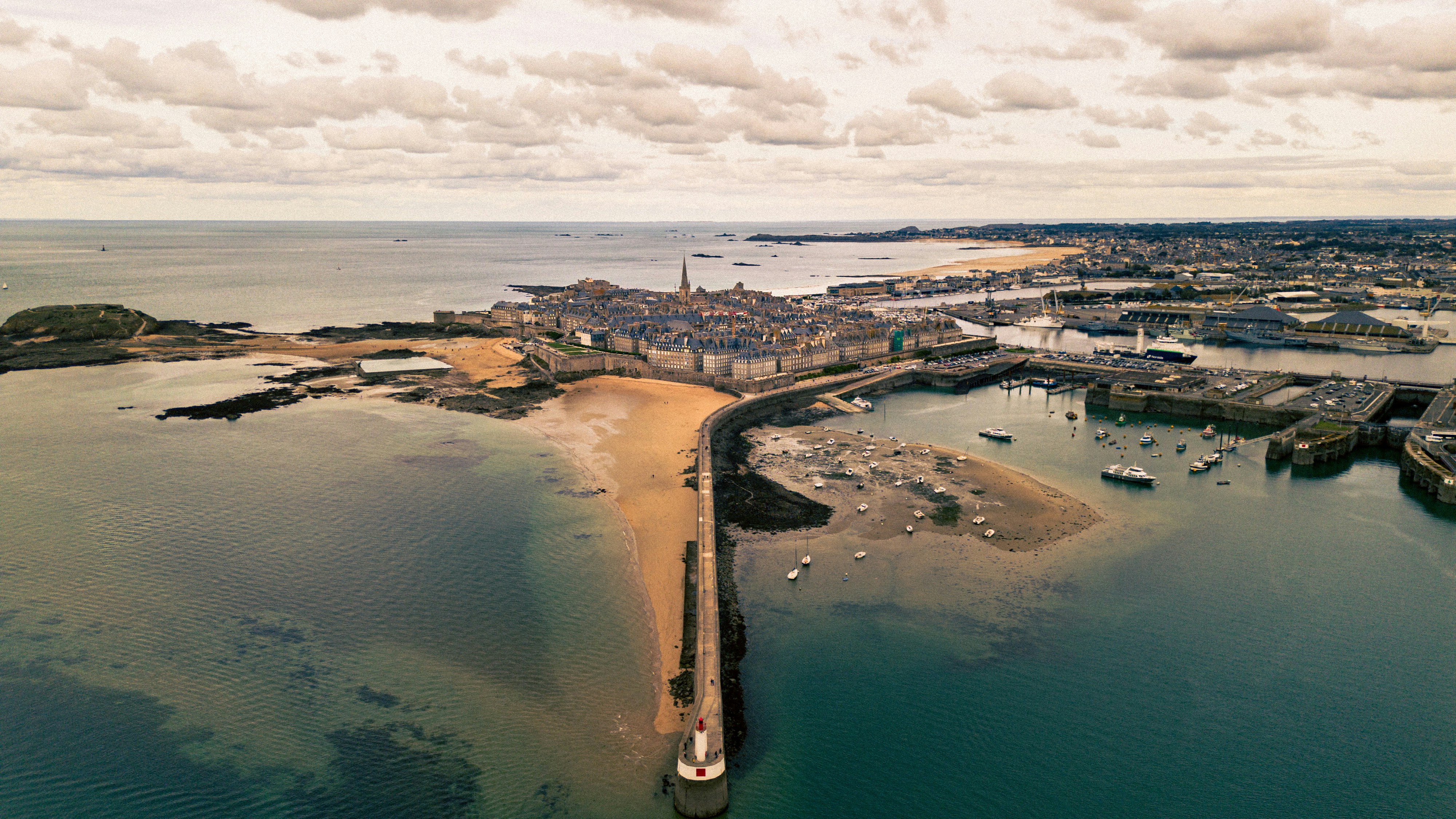 Aerial view of a coastal town with harbor and beach.