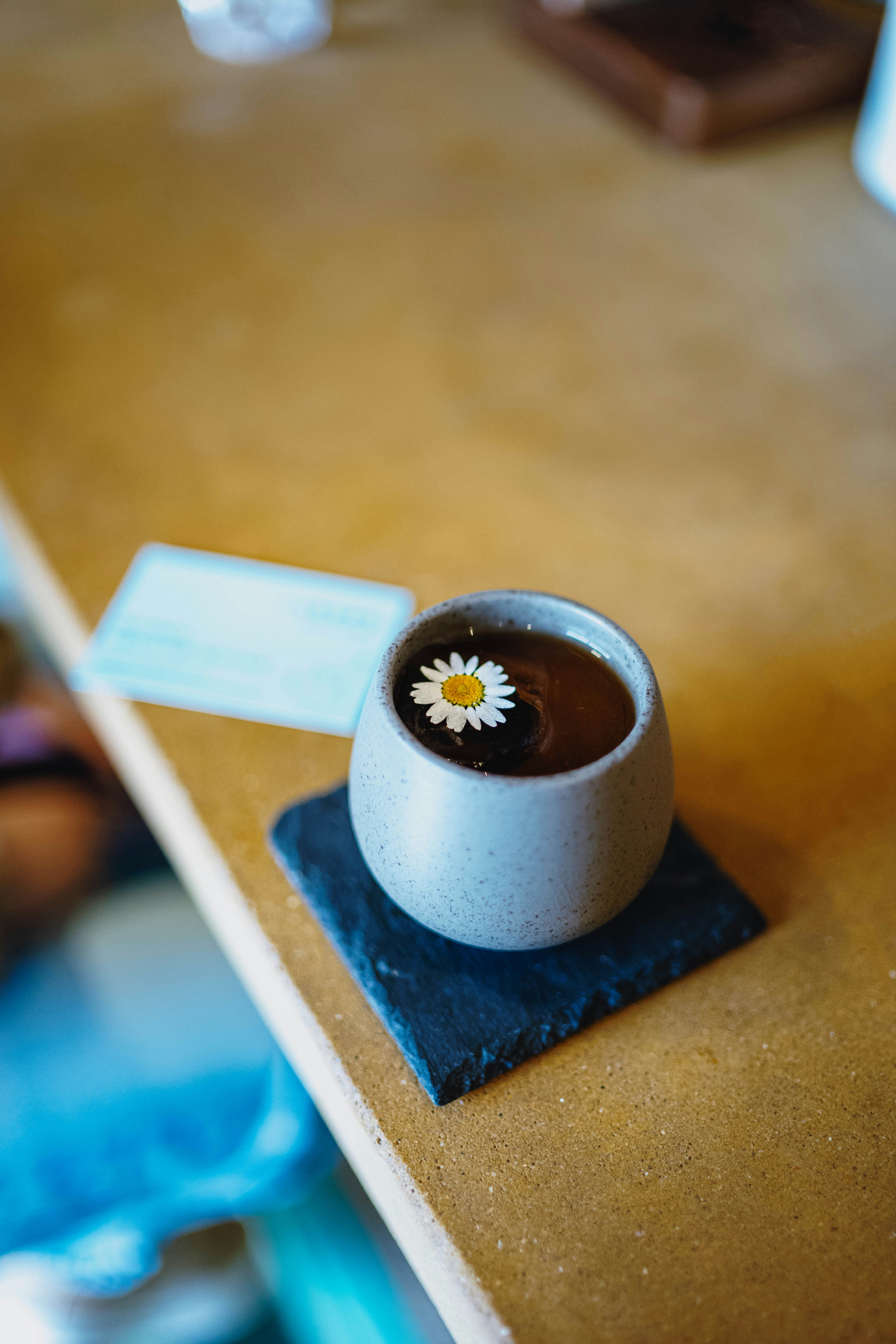Una tazza di tè nero con un fiore di margherita.