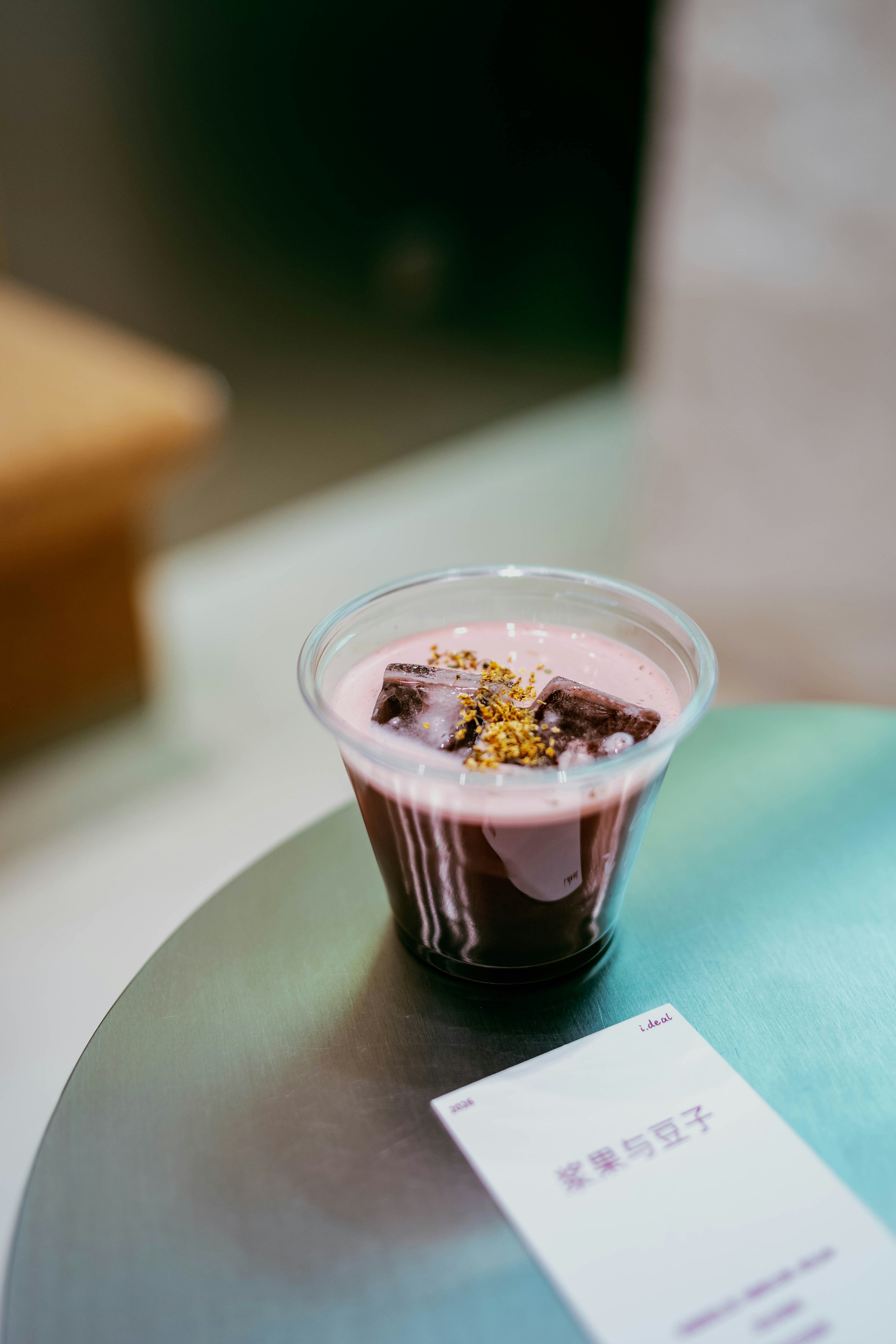 Una bevanda scura guarnita con schiuma rosa e condimenti.