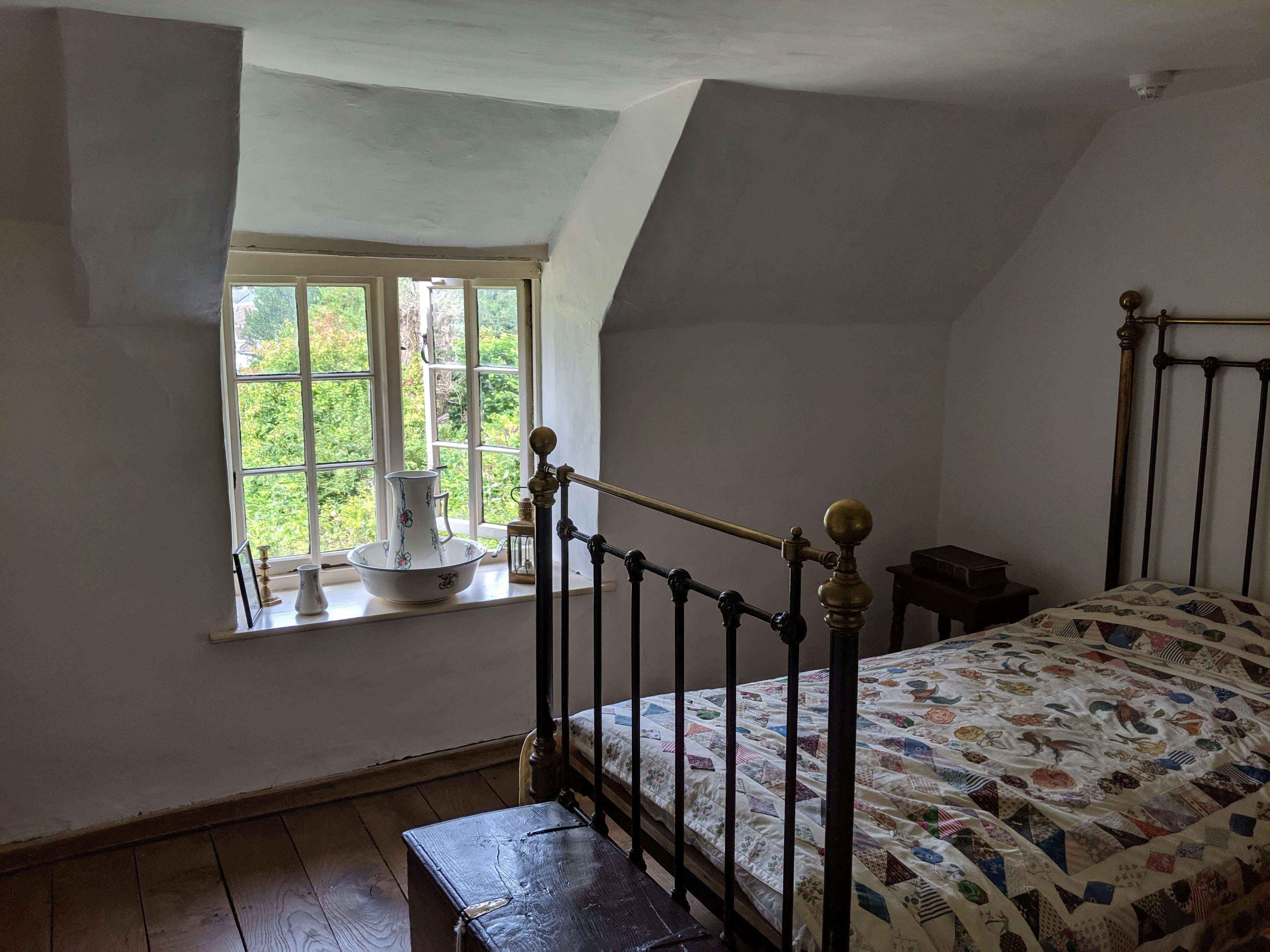 A vintage bedroom with a metal bed frame and window.