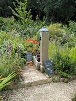 Stone water pump in a lush garden with signs