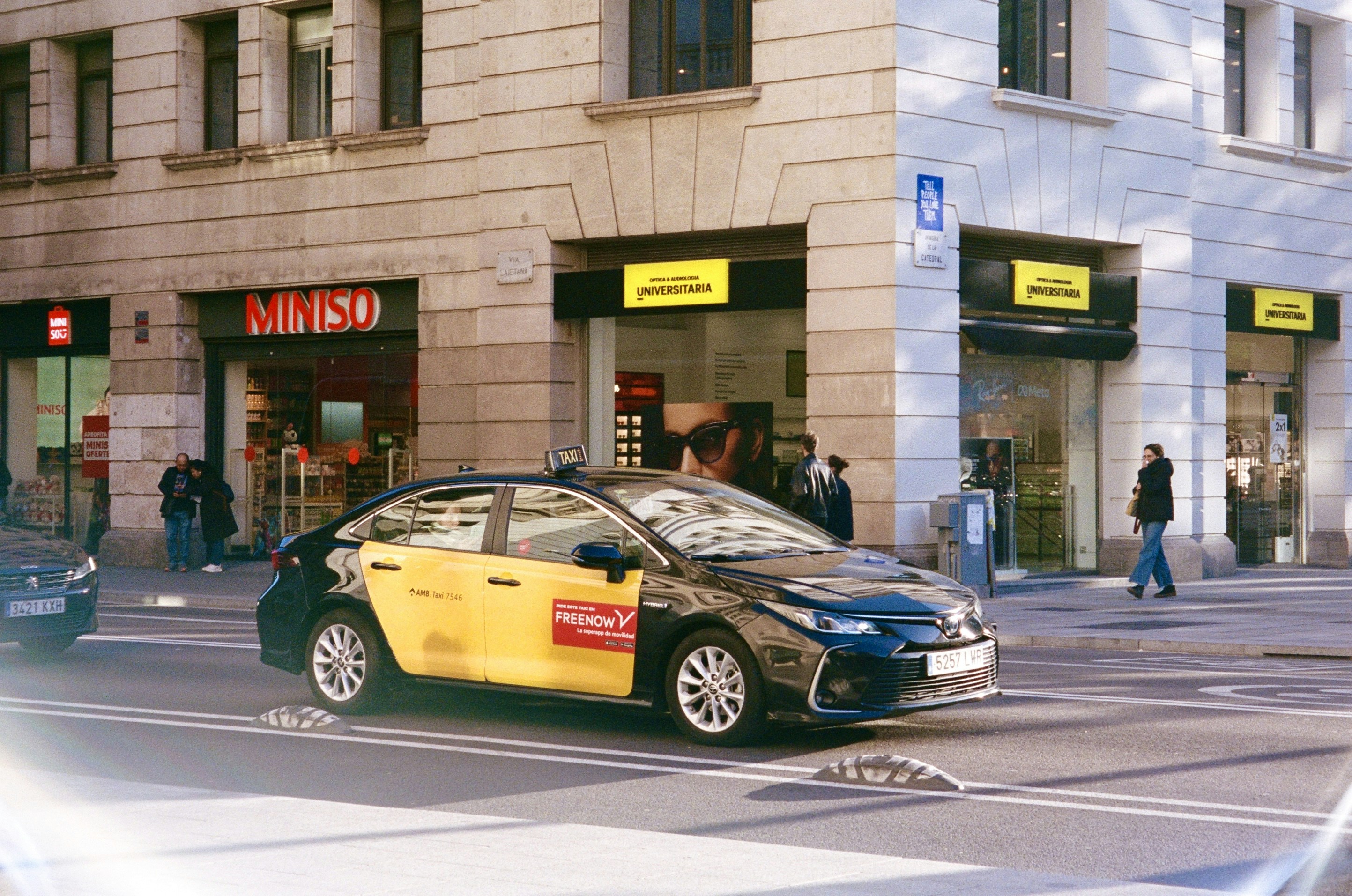 A yellow and black taxi drives down a city street