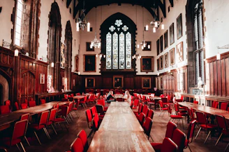 Grand dining hall with wooden tables and red chairs