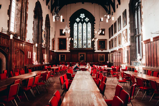 Grand dining hall with wooden tables and red chairs