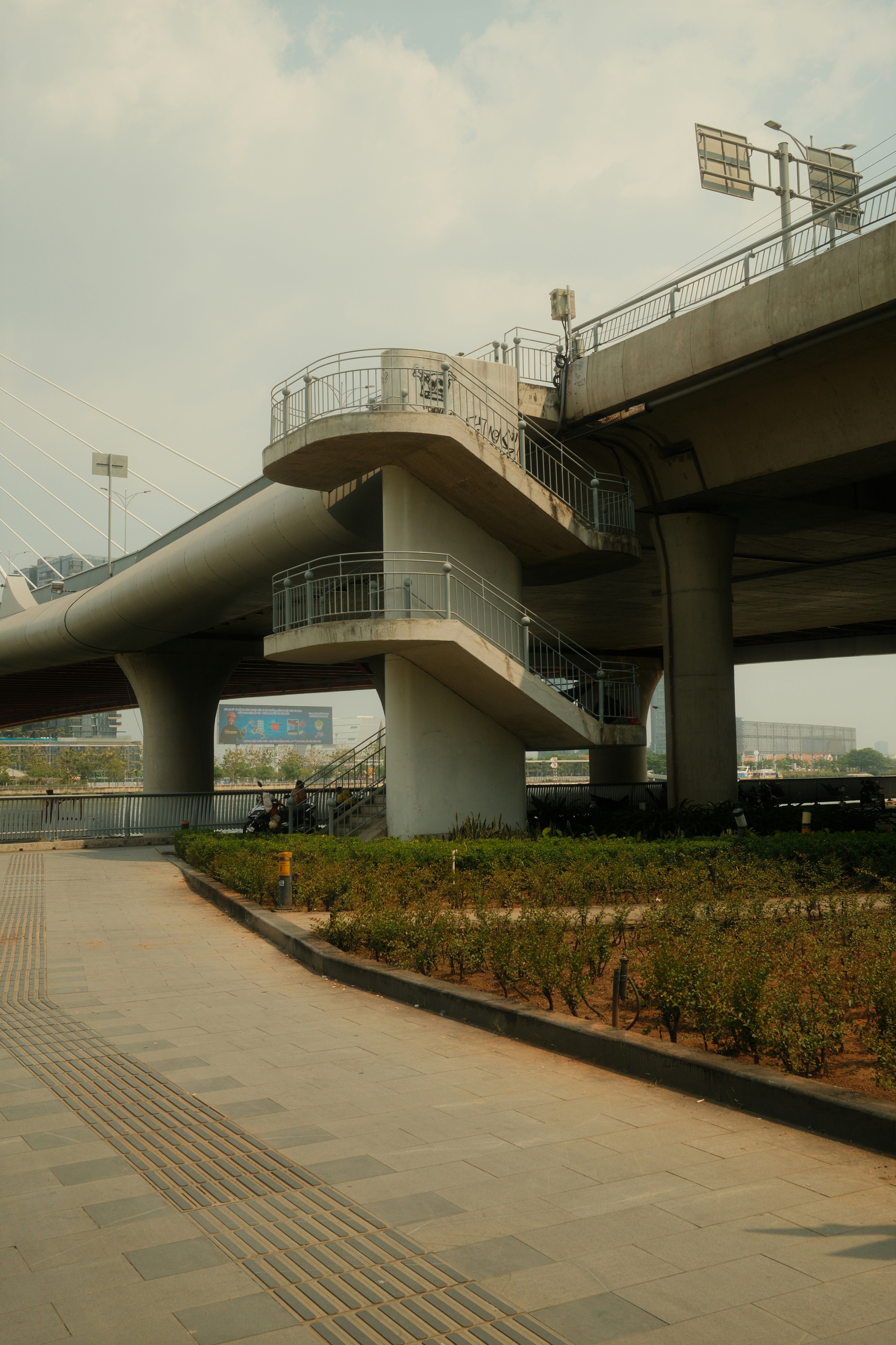 Cavalcavia pedonale in cemento con scale e ringhiere.