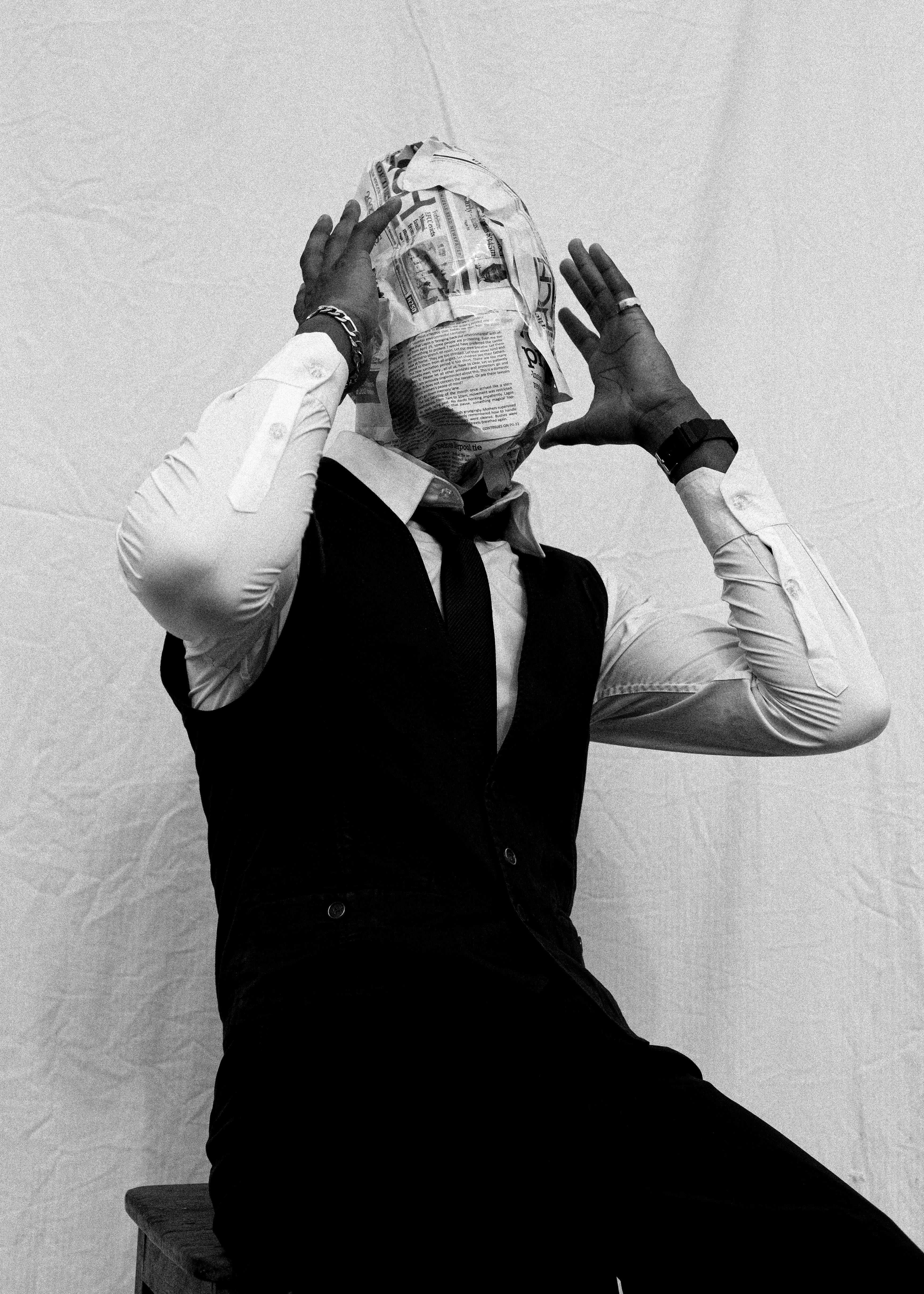 Man wearing a newspaper mask and formal attire