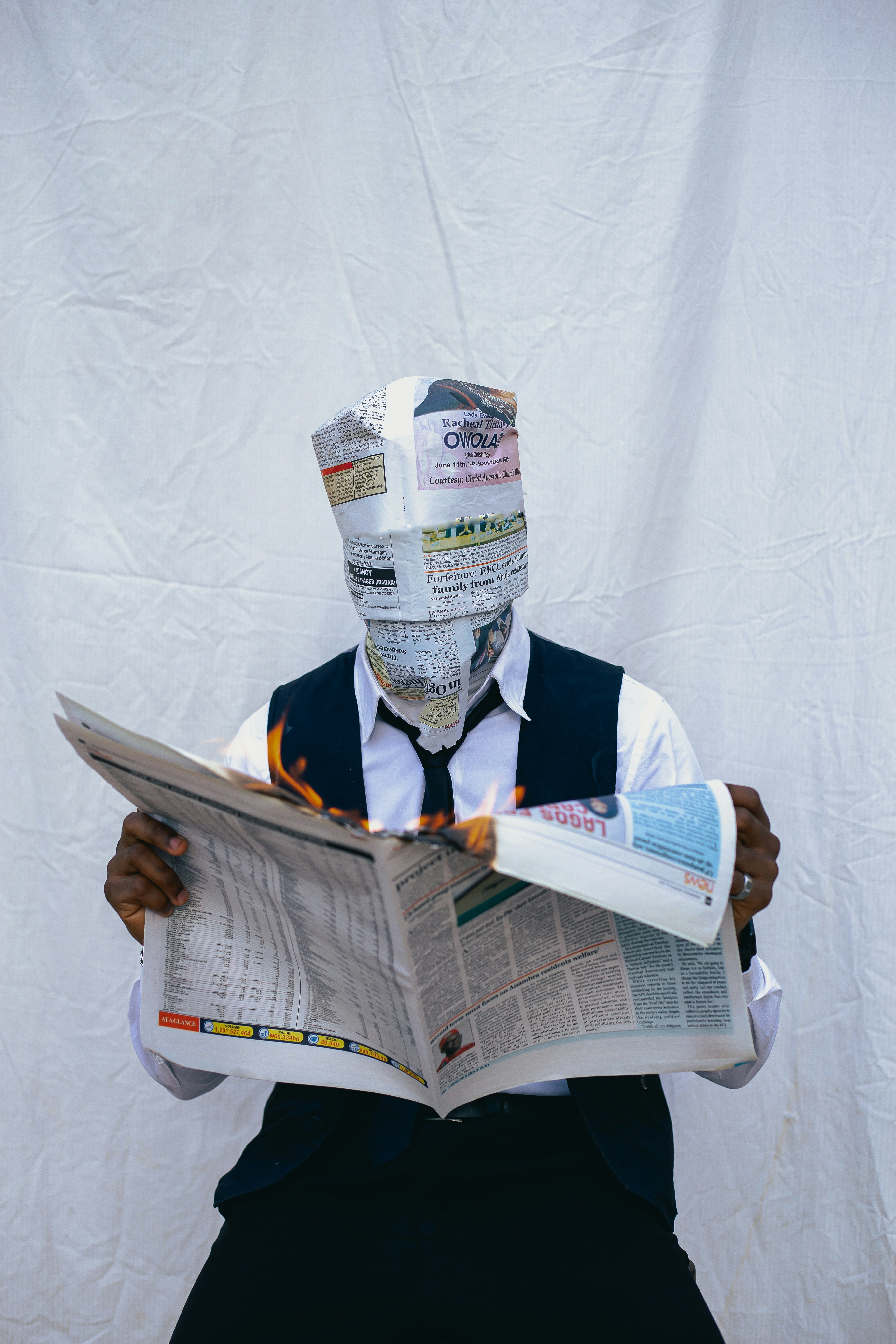 Person with newspaper-covered head reading newspaper.