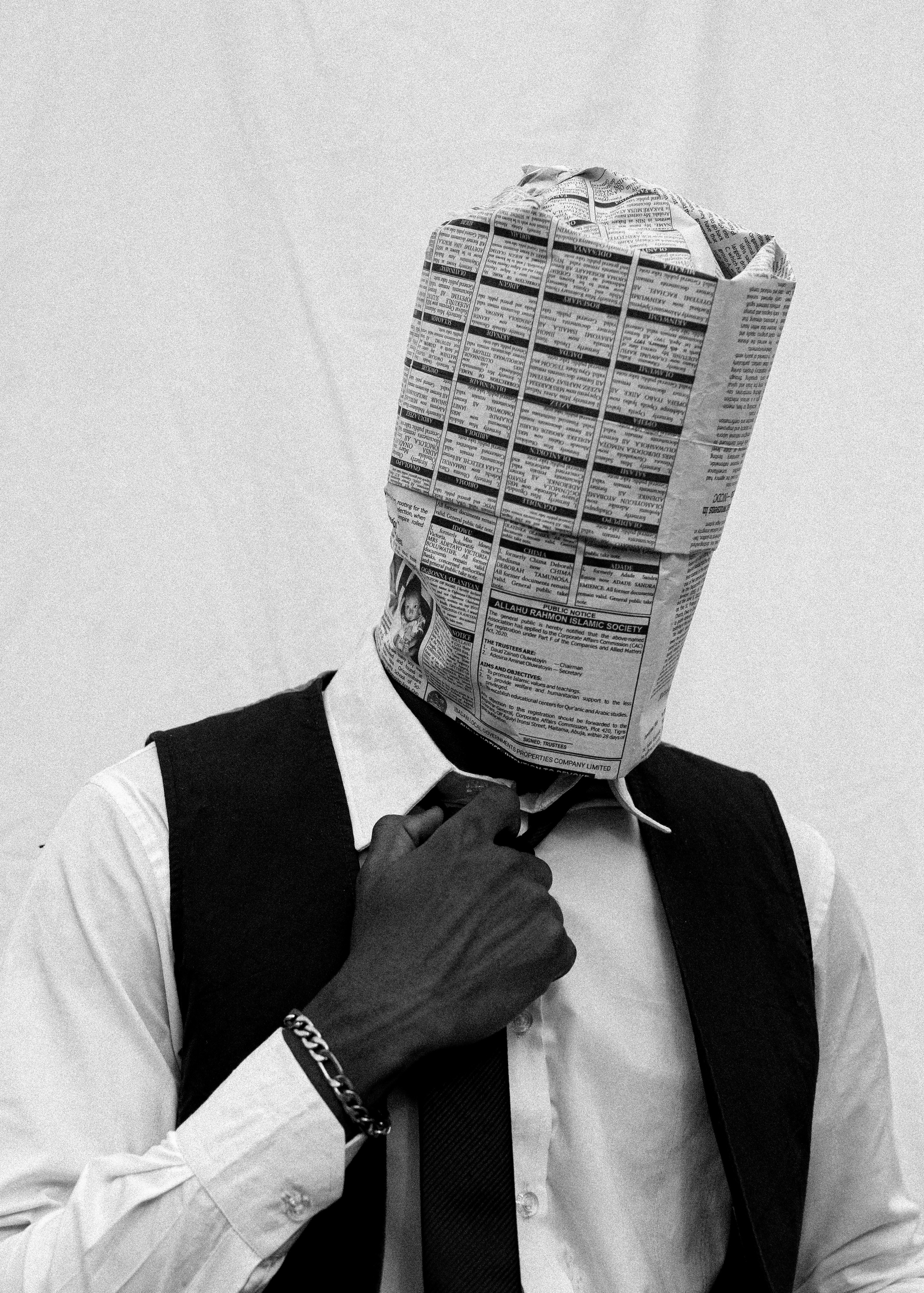 Man with newspaper over head adjusting tie