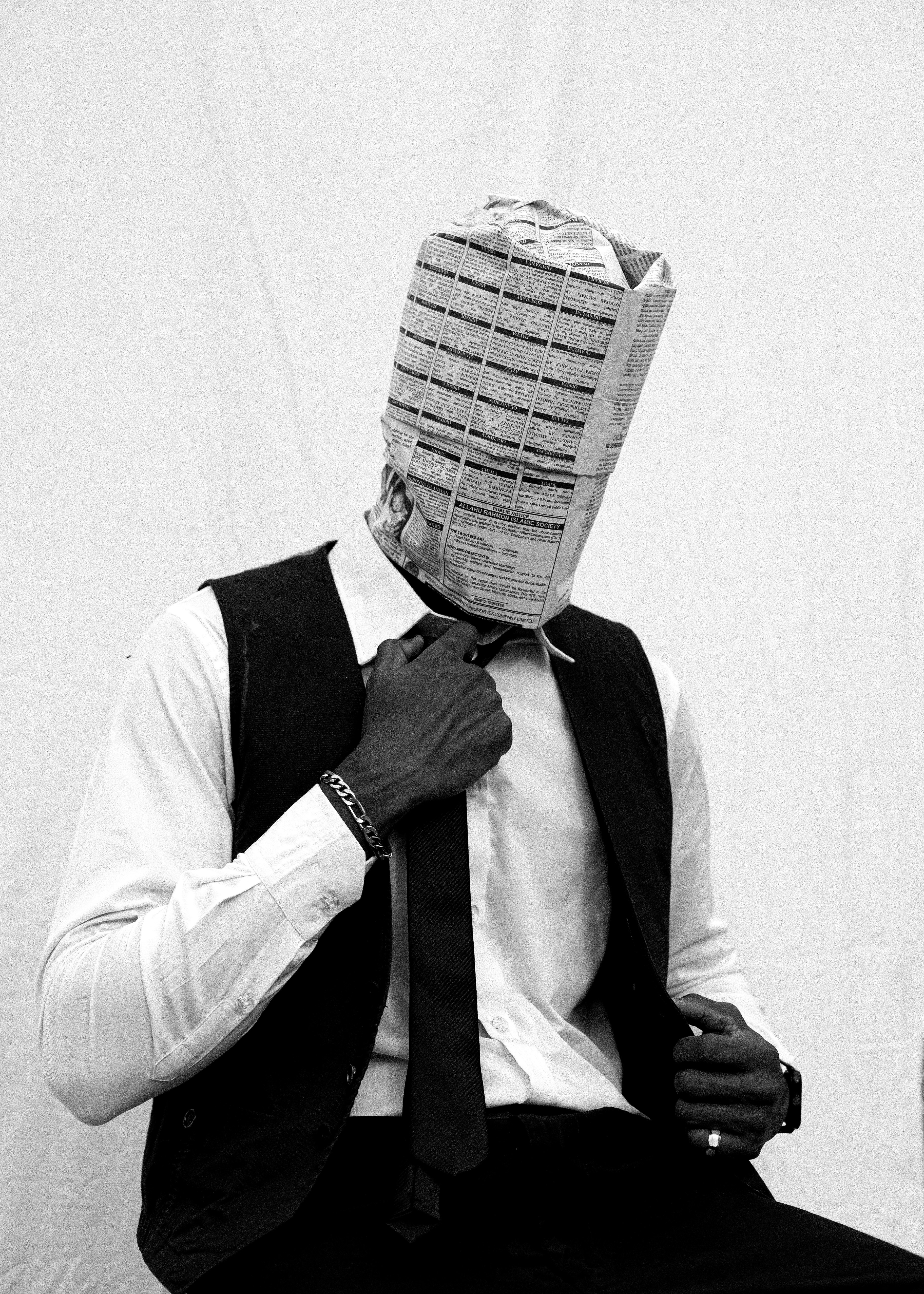 Man in suit with newspaper over head adjusting tie